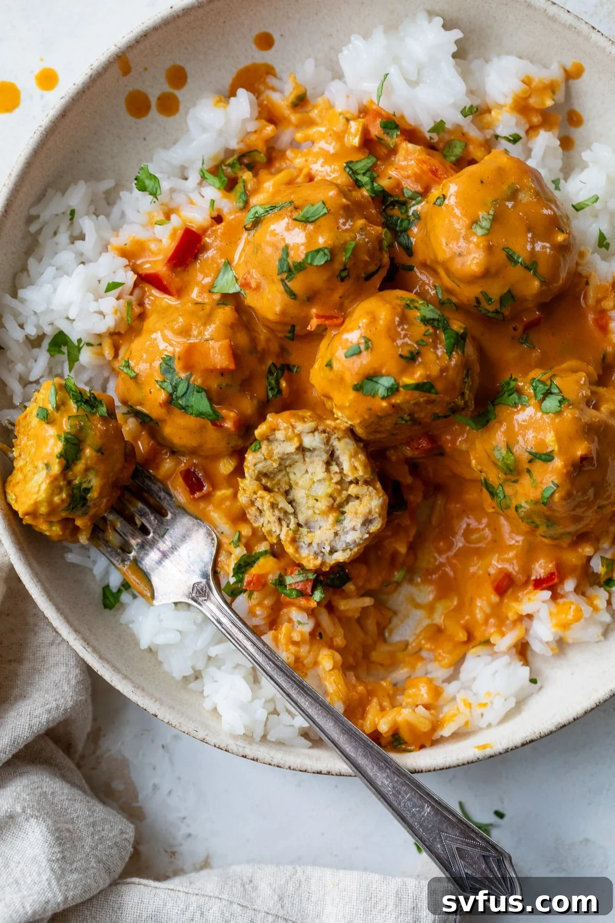 coconut curry meatballs over rice on a plate with a fork