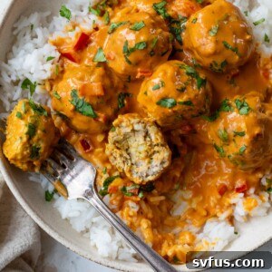coconut curry meatballs over rice on a plate with a fork