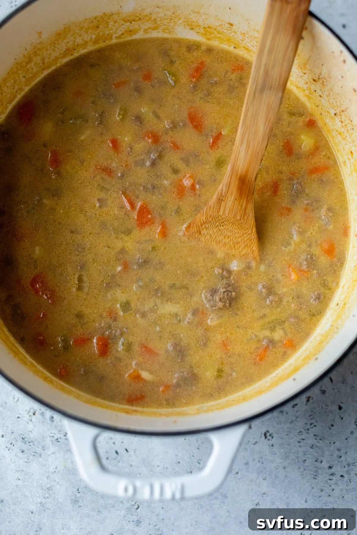 cheeseburger soup in a dutch oven with a wooden spoon