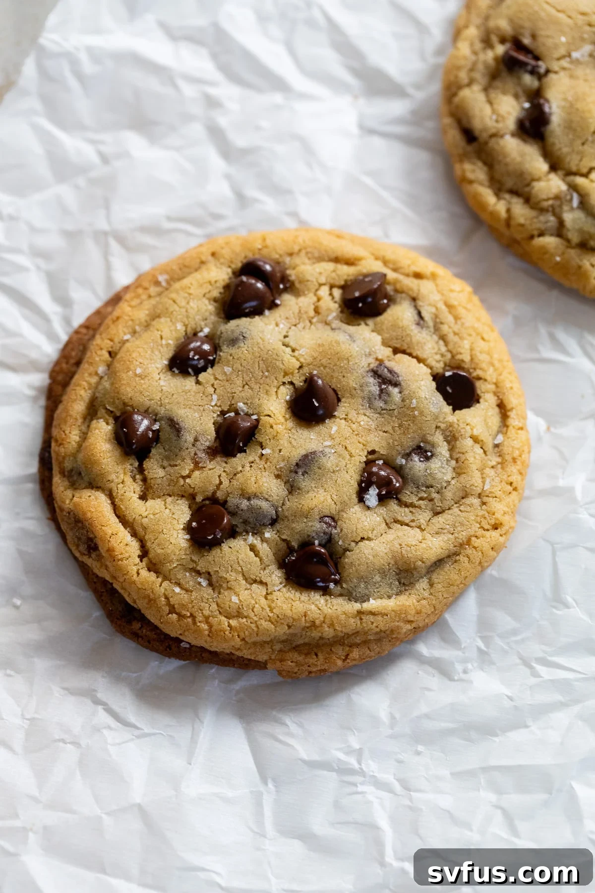 A freshly baked single-serve chocolate chip cookie resting on parchment paper, ready to be enjoyed.