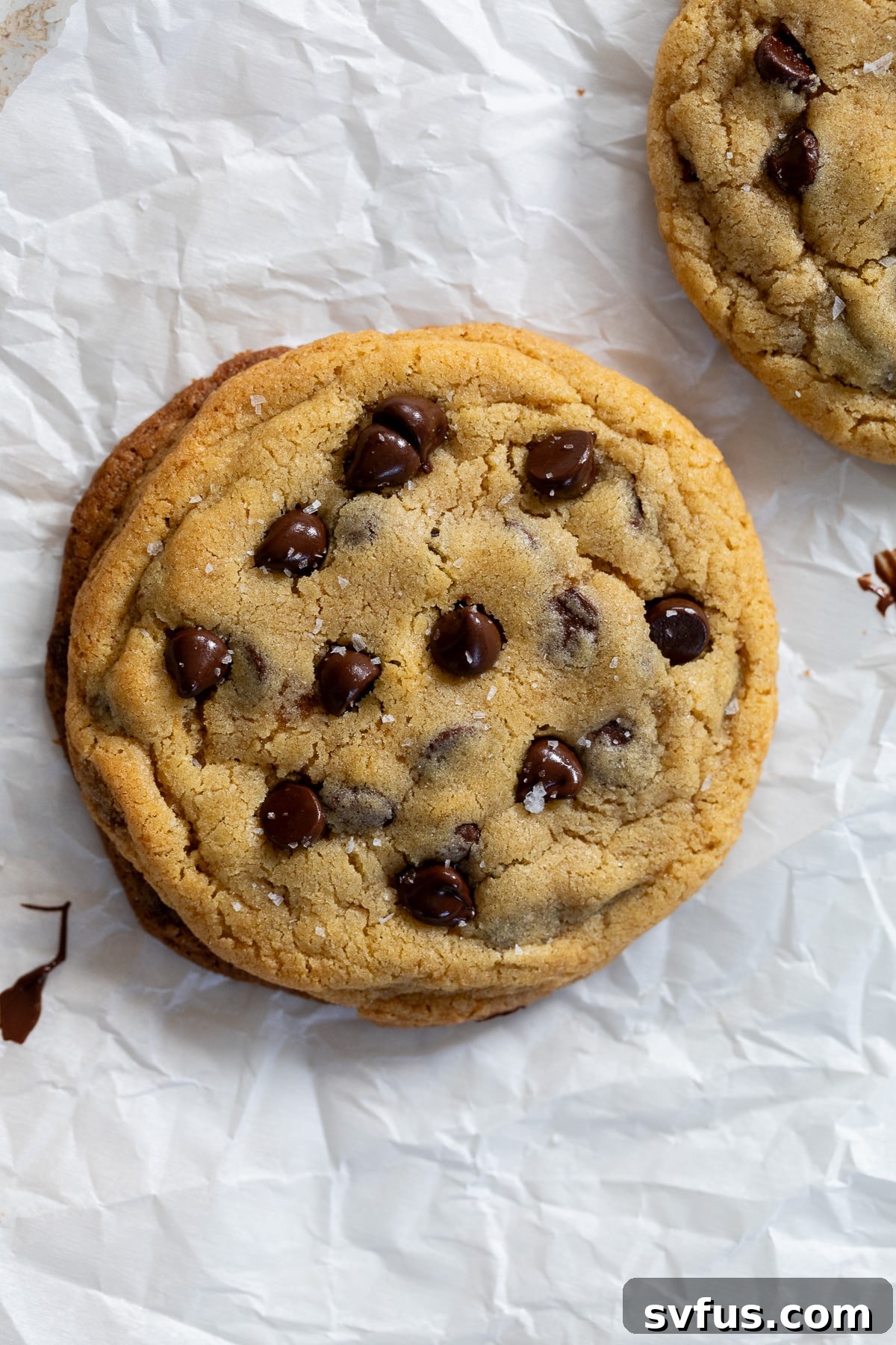 A freshly baked single-serve chocolate chip cookie resting on parchment paper, ready to be enjoyed.