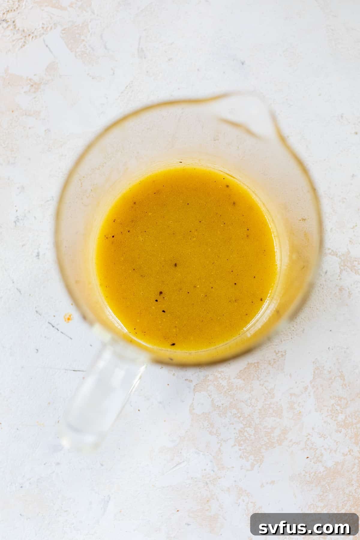 Homemade vinaigrette dressing being whisked in a glass measuring cup.
