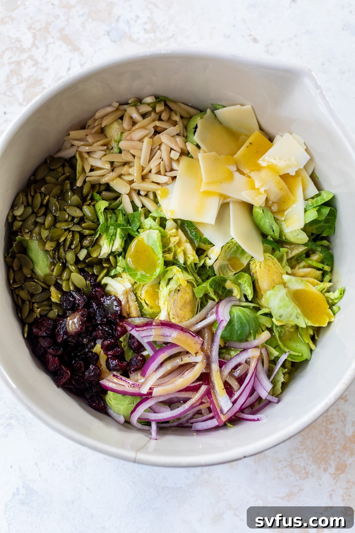 All the fresh ingredients for Brussels Sprouts Slaw combined in a large bowl, ready for dressing.