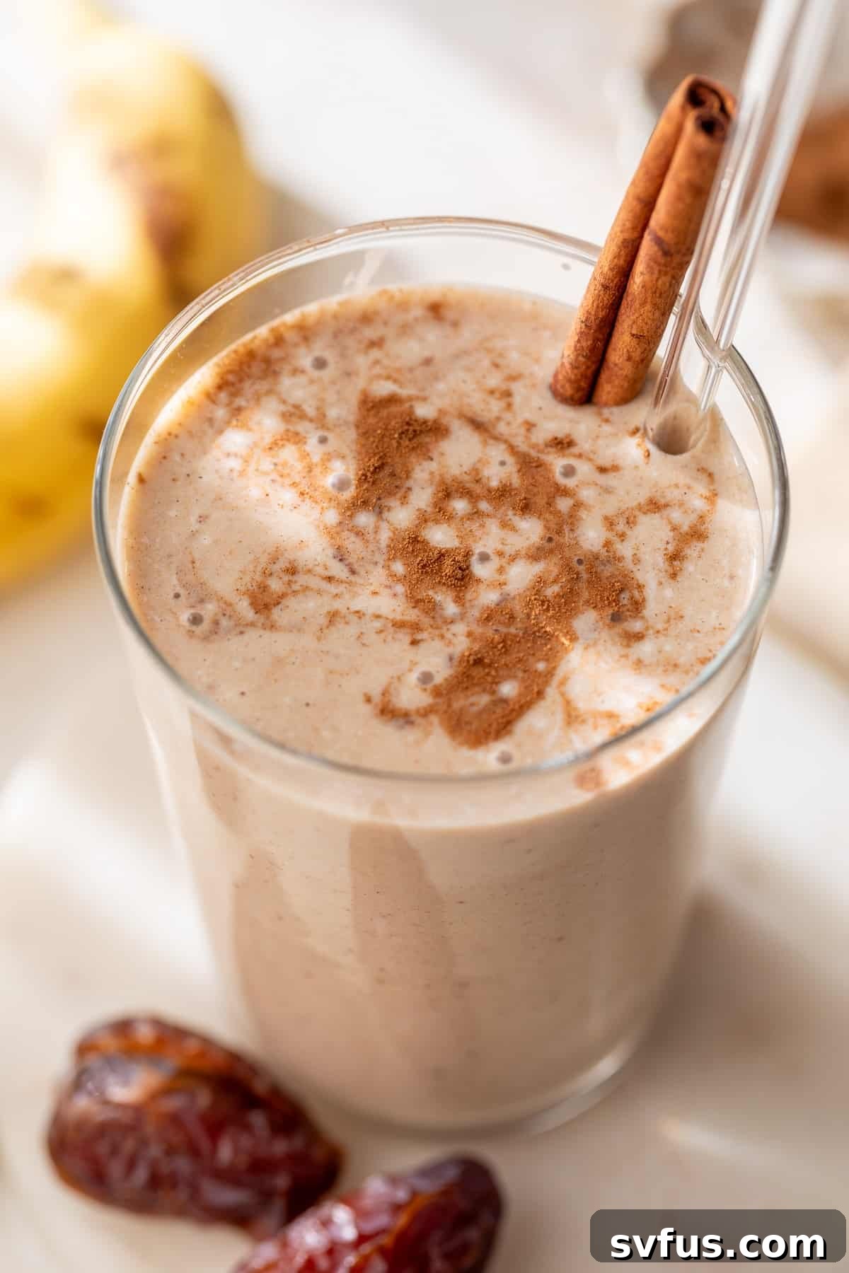 date smoothie in a glass with a straw and cinnamon stick, garnished with a cinnamon stick