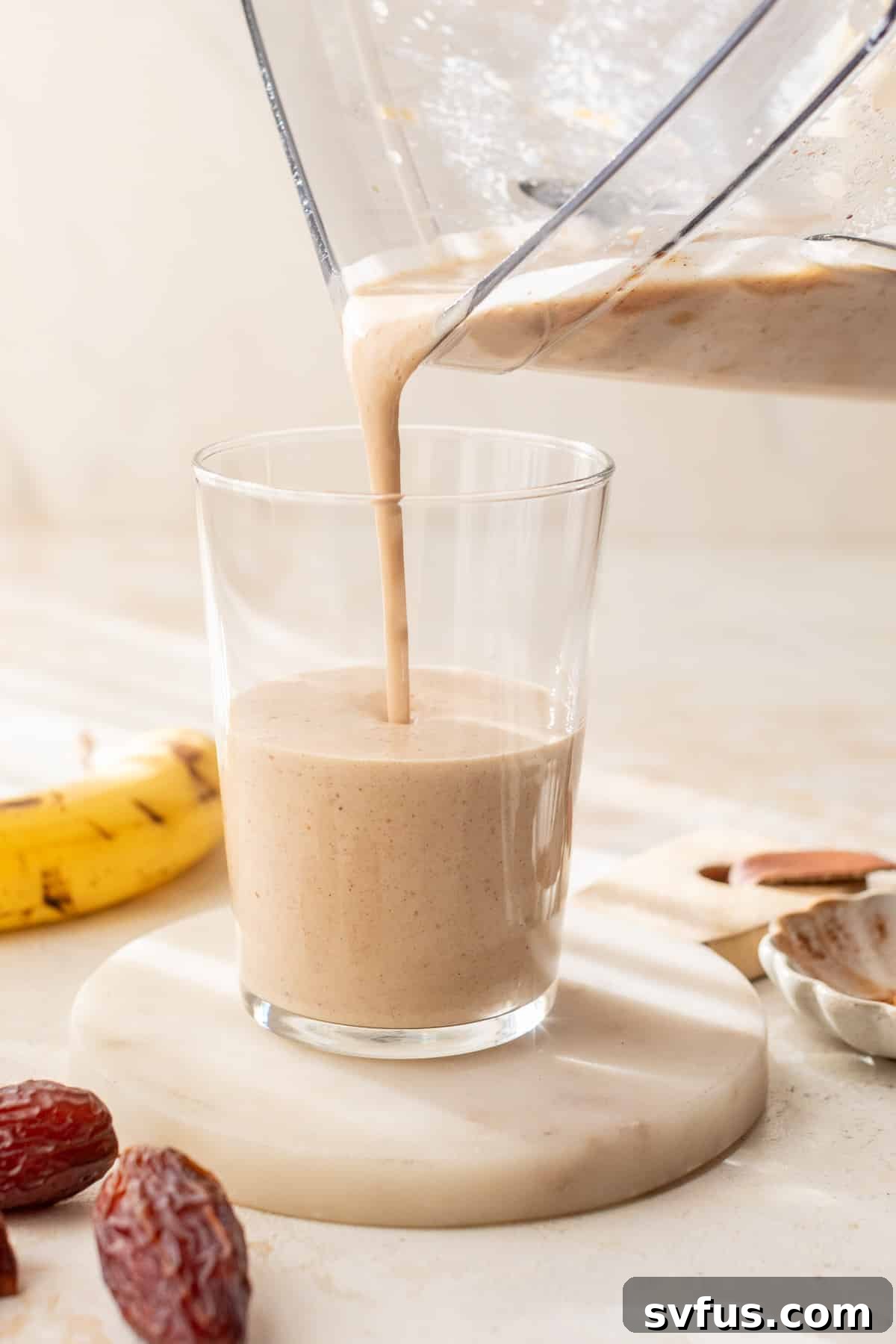 Date smoothie being poured into a tall glass from a blender