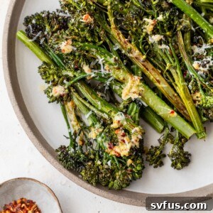 Roasted broccolini on a plate, garnished with fresh lemon wedges.