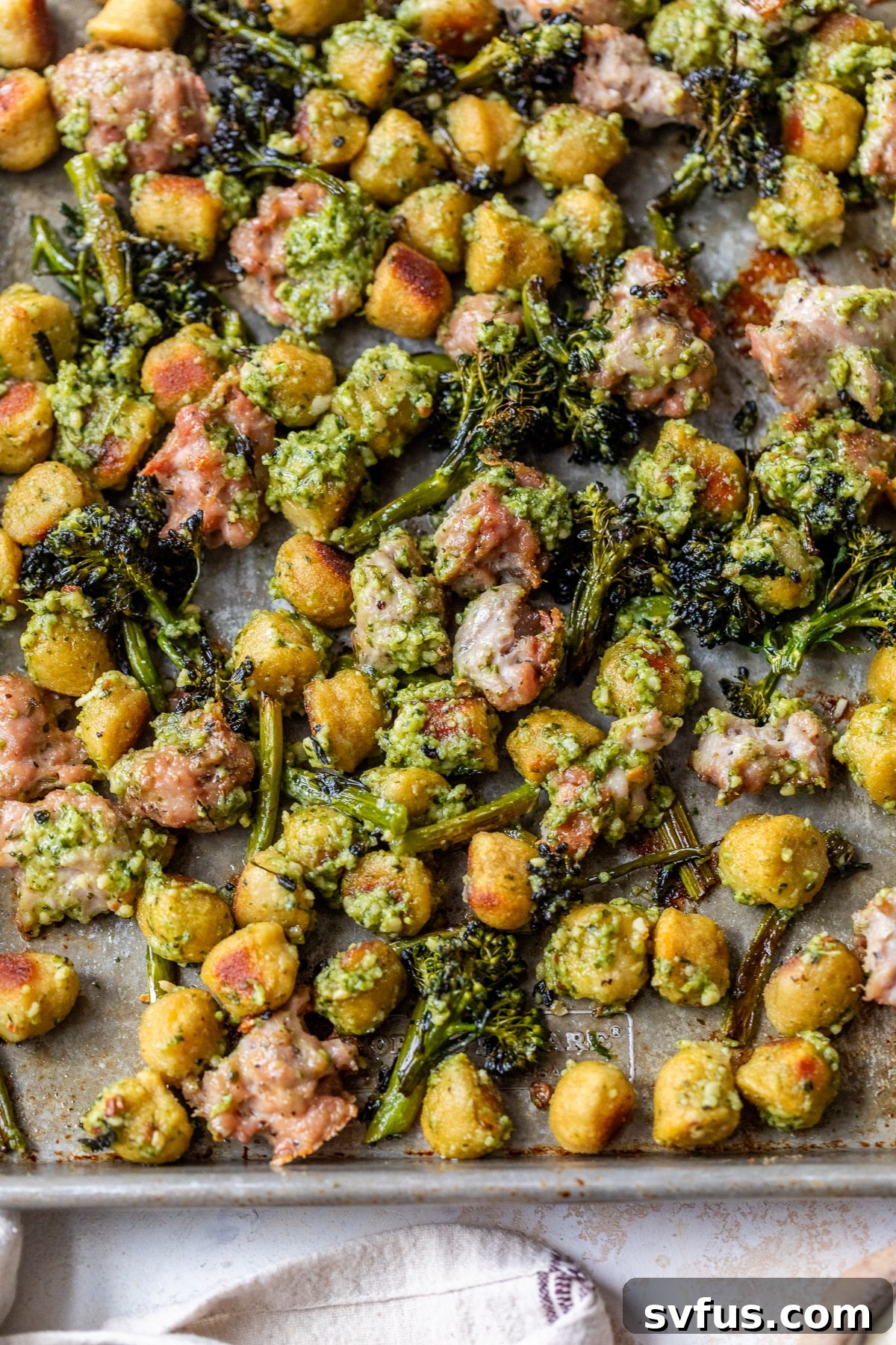 The completed Sheet Pan Gnocchi with sausage and broccolini, tossed in pesto cream sauce, served in a bowl.
