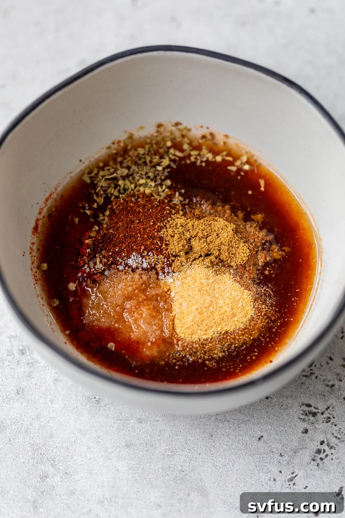 A small bowl containing the vibrant red chipotle marinade, showcasing its rich texture and color.