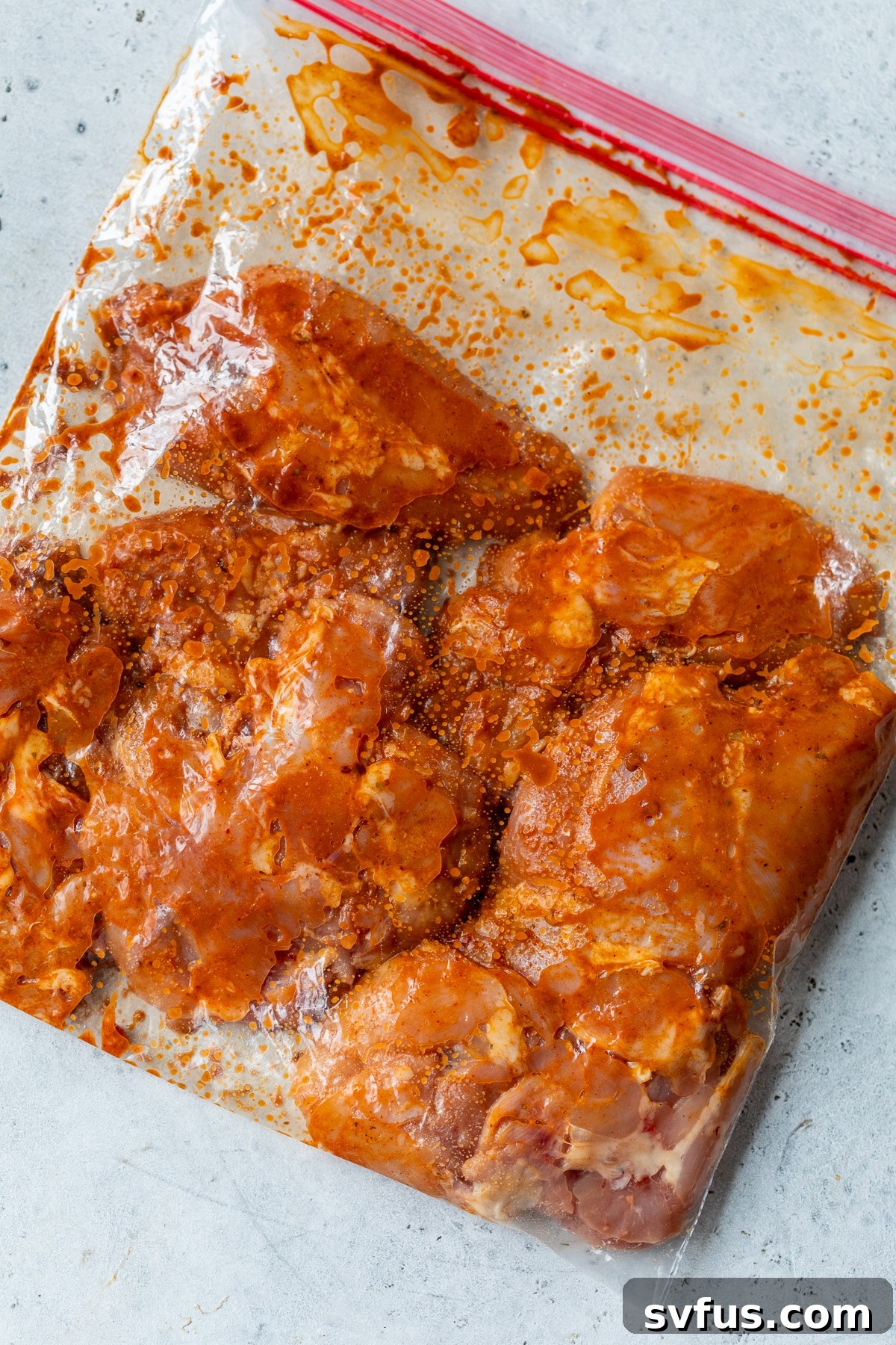 Boneless chicken thighs soaking in the chipotle marinade inside a large ziplock bag, ensuring even coating.