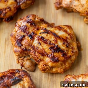 Close-up of perfectly grilled chipotle chicken thighs on a bamboo cutting board, garnished with fresh cilantro.