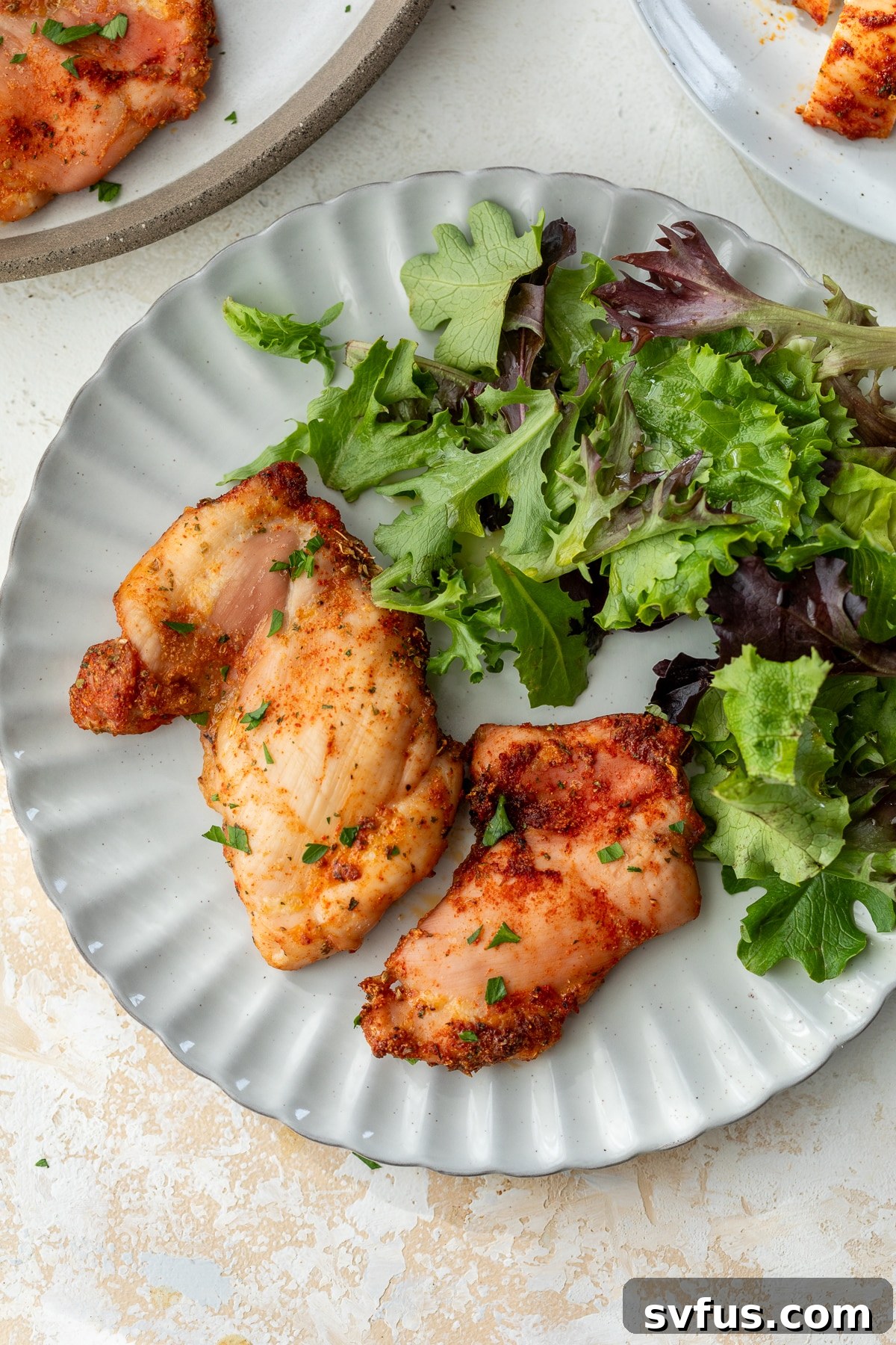baked boneless chicken thighs on a plate with mixed greens