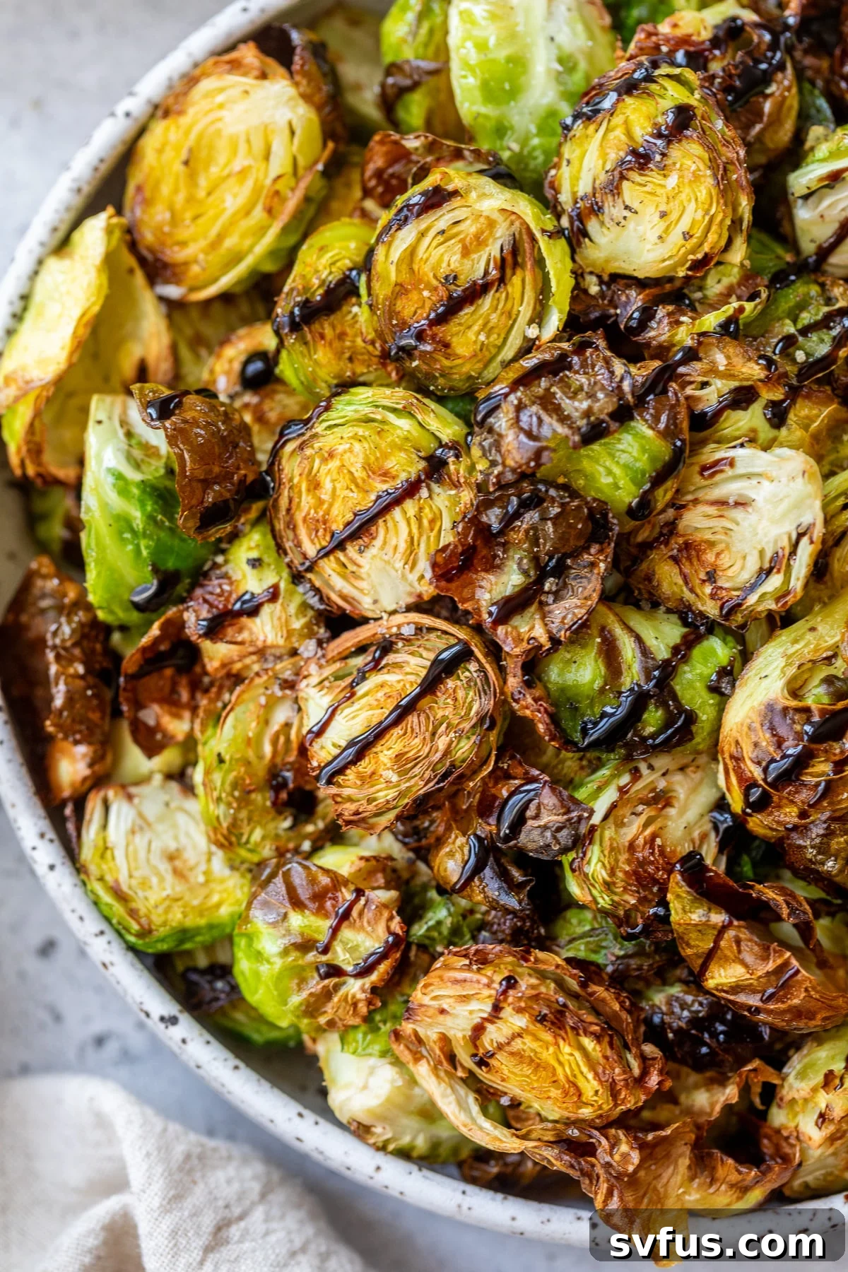 Crispy Air Fryer Brussels Sprouts in a serving bowl, beautifully coated with a balsamic glaze and fresh herbs