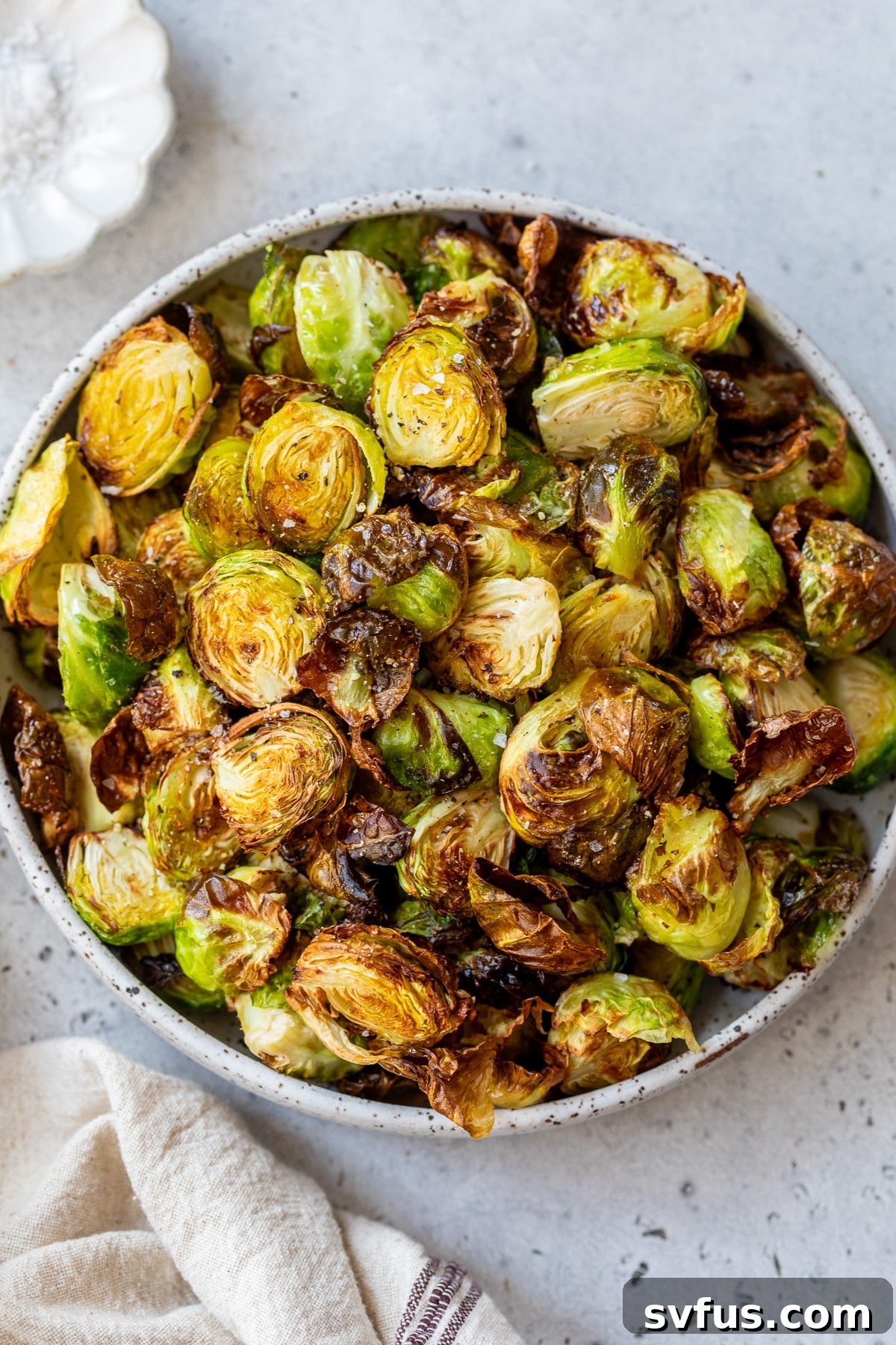 A bowl of freshly air-fried Brussels sprouts, glistening with a drizzle of balsamic honey sauce