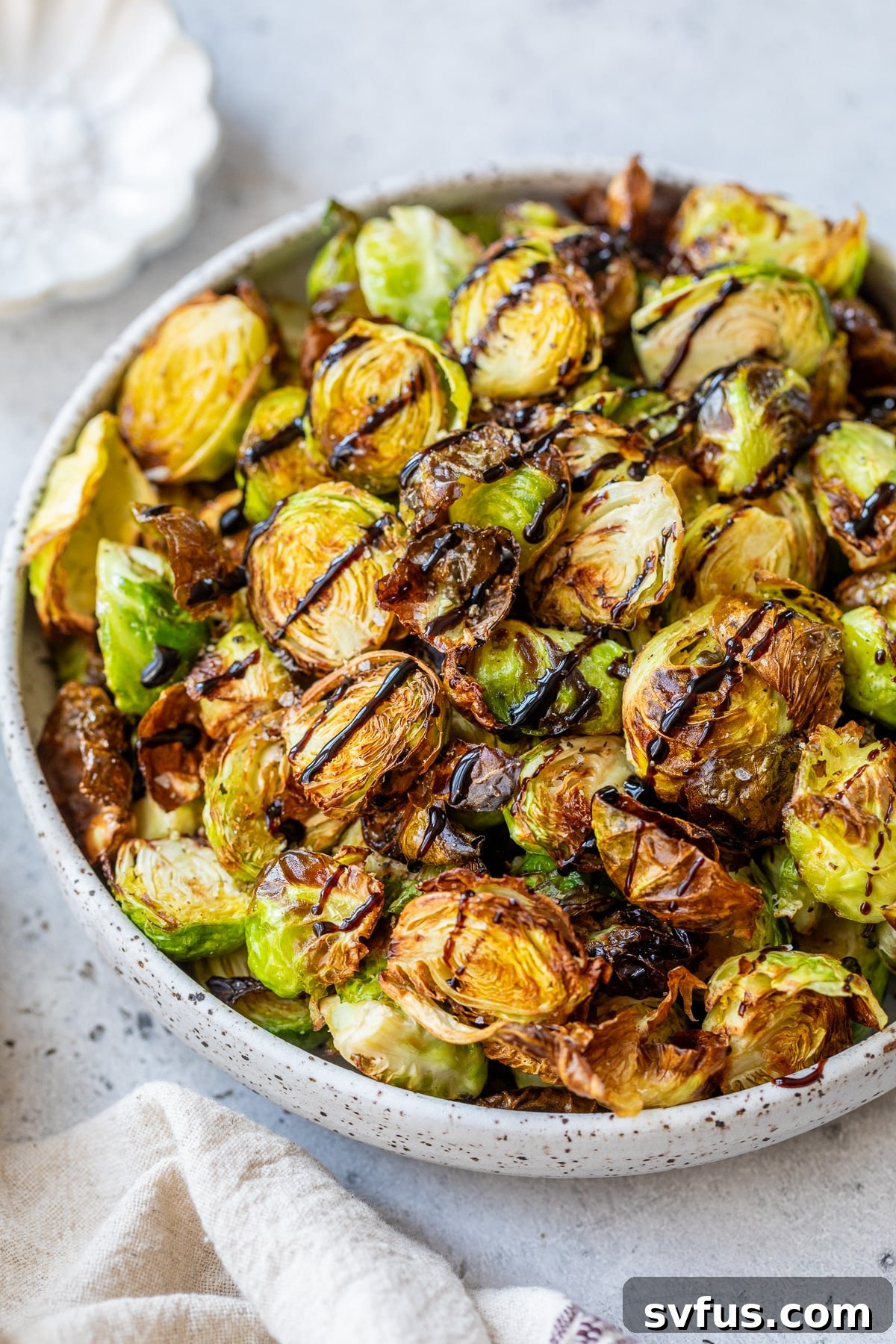 Close-up shot of crispy air fryer Brussels sprouts in a bowl, drizzled with a rich balsamic glaze and ready to serve