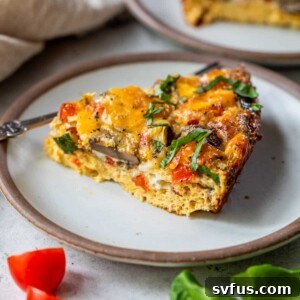 A slice of a crustless vegetable quiche on a white plate, ready to be served.