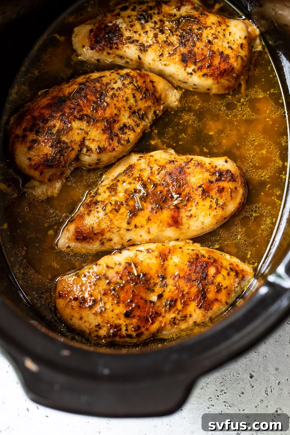 chicken breasts cooking in a slow cooker.