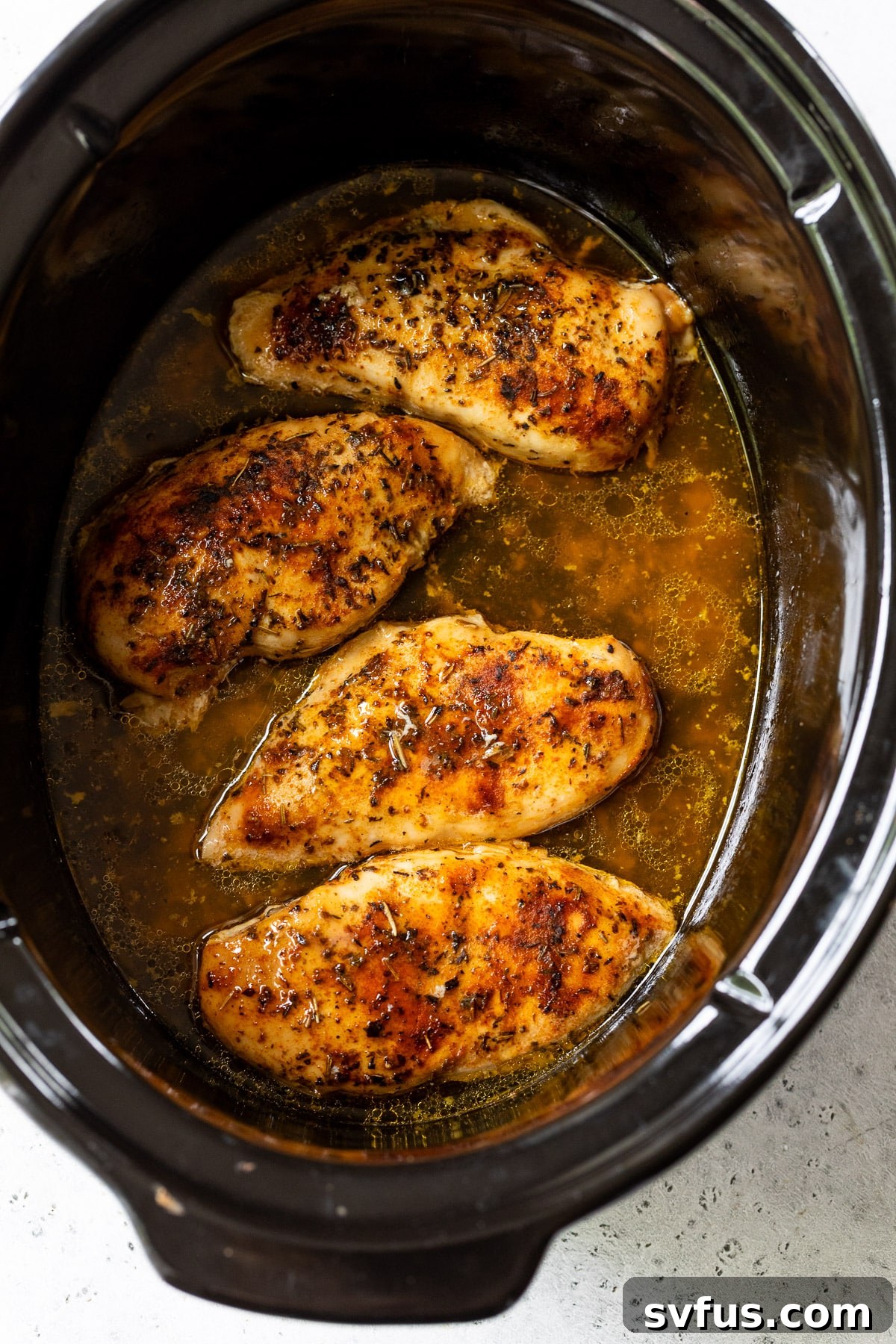 chicken breasts cooking in a slow cooker.
