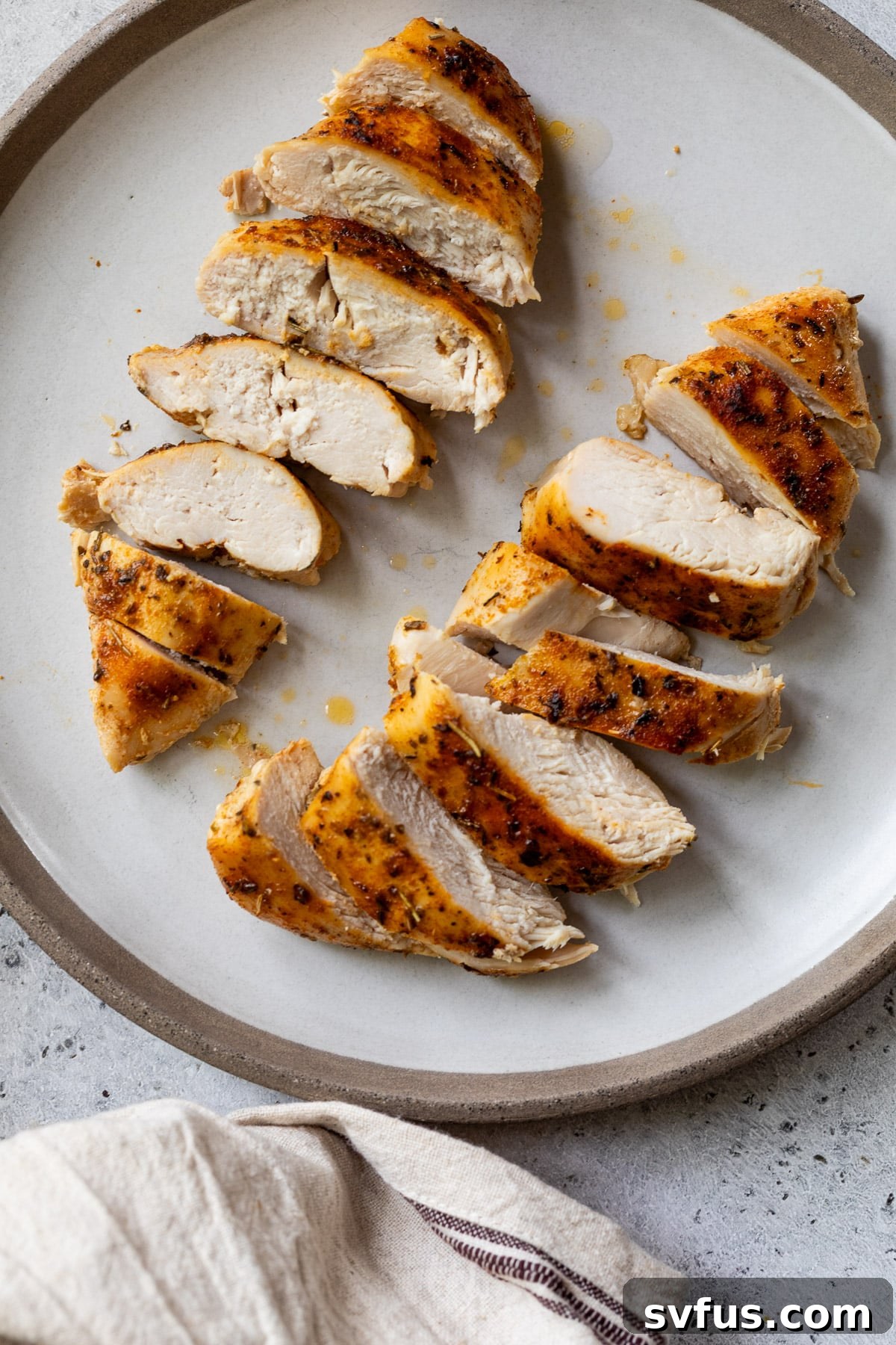 two sliced chicken breasts on a white plate.