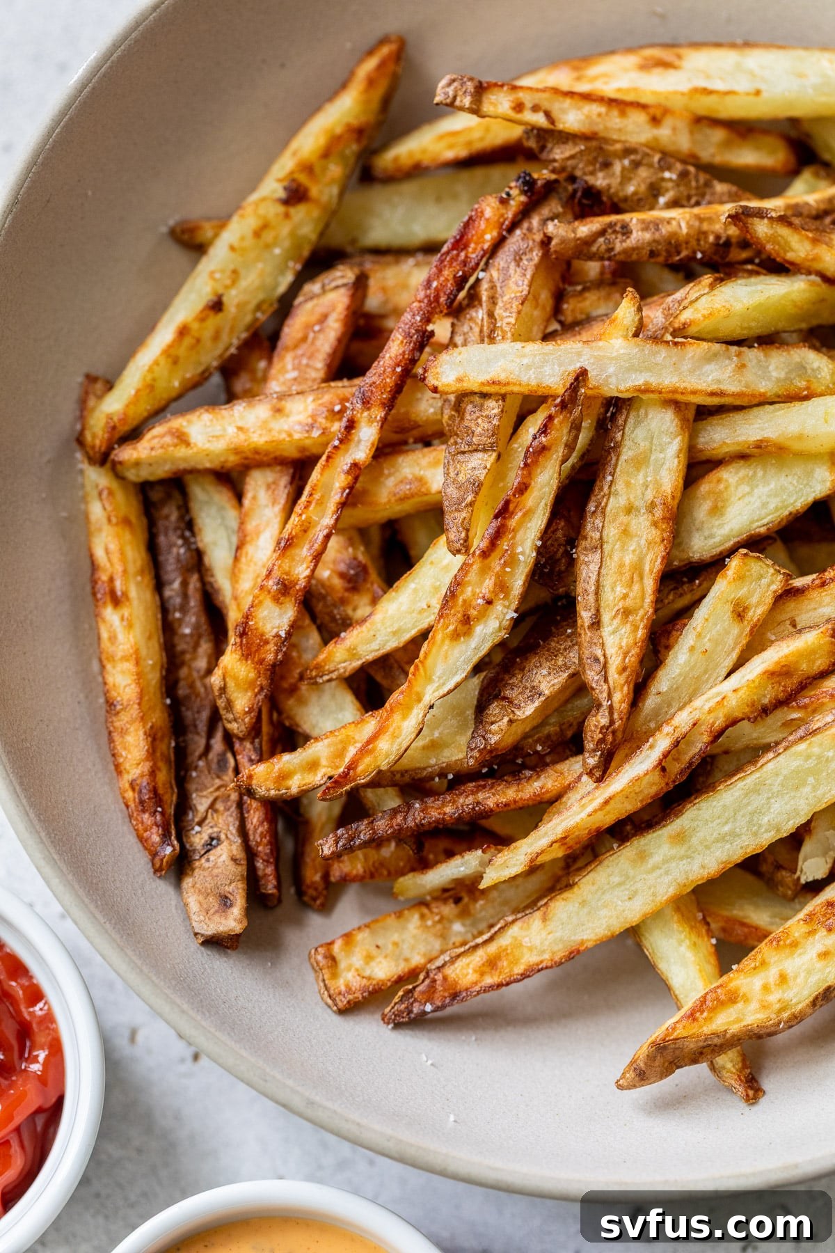 A beautifully arranged bowl of crispy air fryer french fries, garnished and ready for serving.