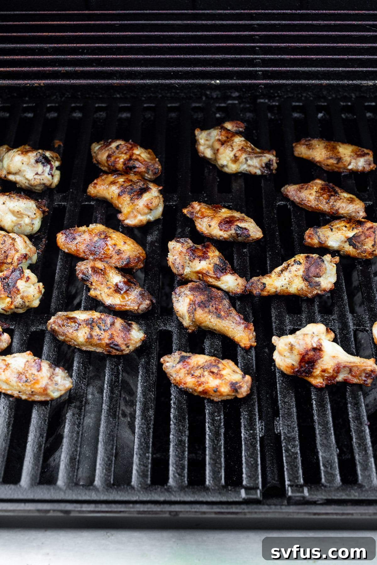 cooking rows of chicken wings on a grill.