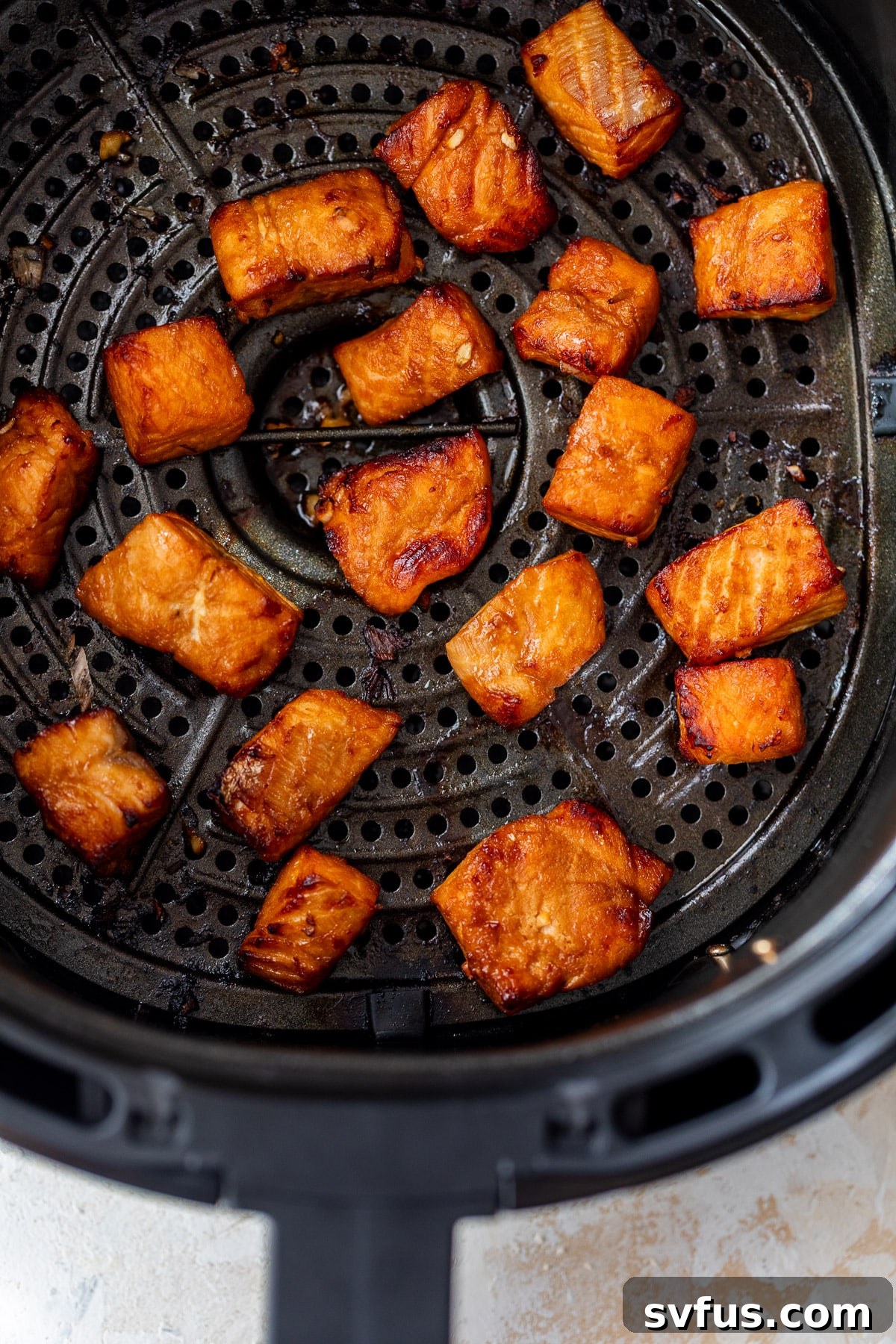 Perfectly cooked, golden-brown air fryer salmon bites, crisp on the outside and tender within, resting in the air fryer basket after cooking.