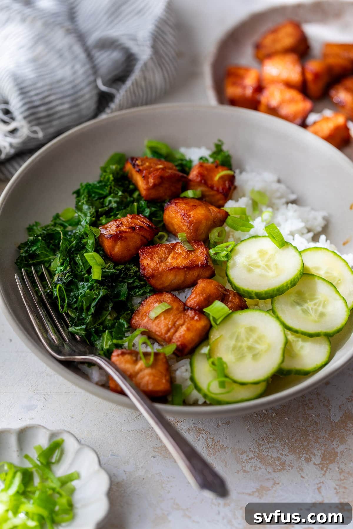 A vibrant bowl featuring perfectly cooked air fryer salmon bites, crisp cucumber slices, fresh kale, and fluffy rice, ready to be enjoyed as a complete meal.