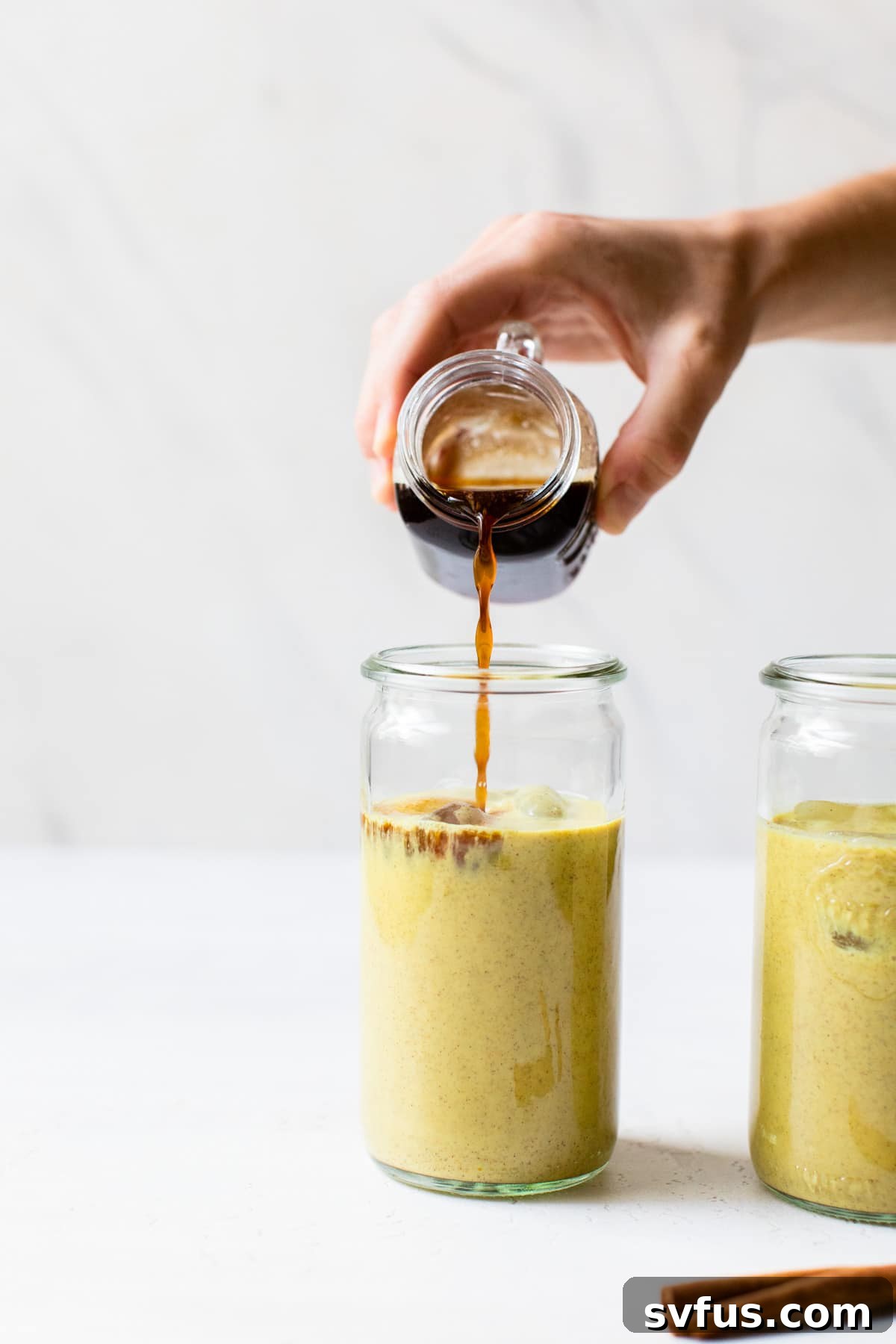 Pouring espresso into an iced turmeric latte