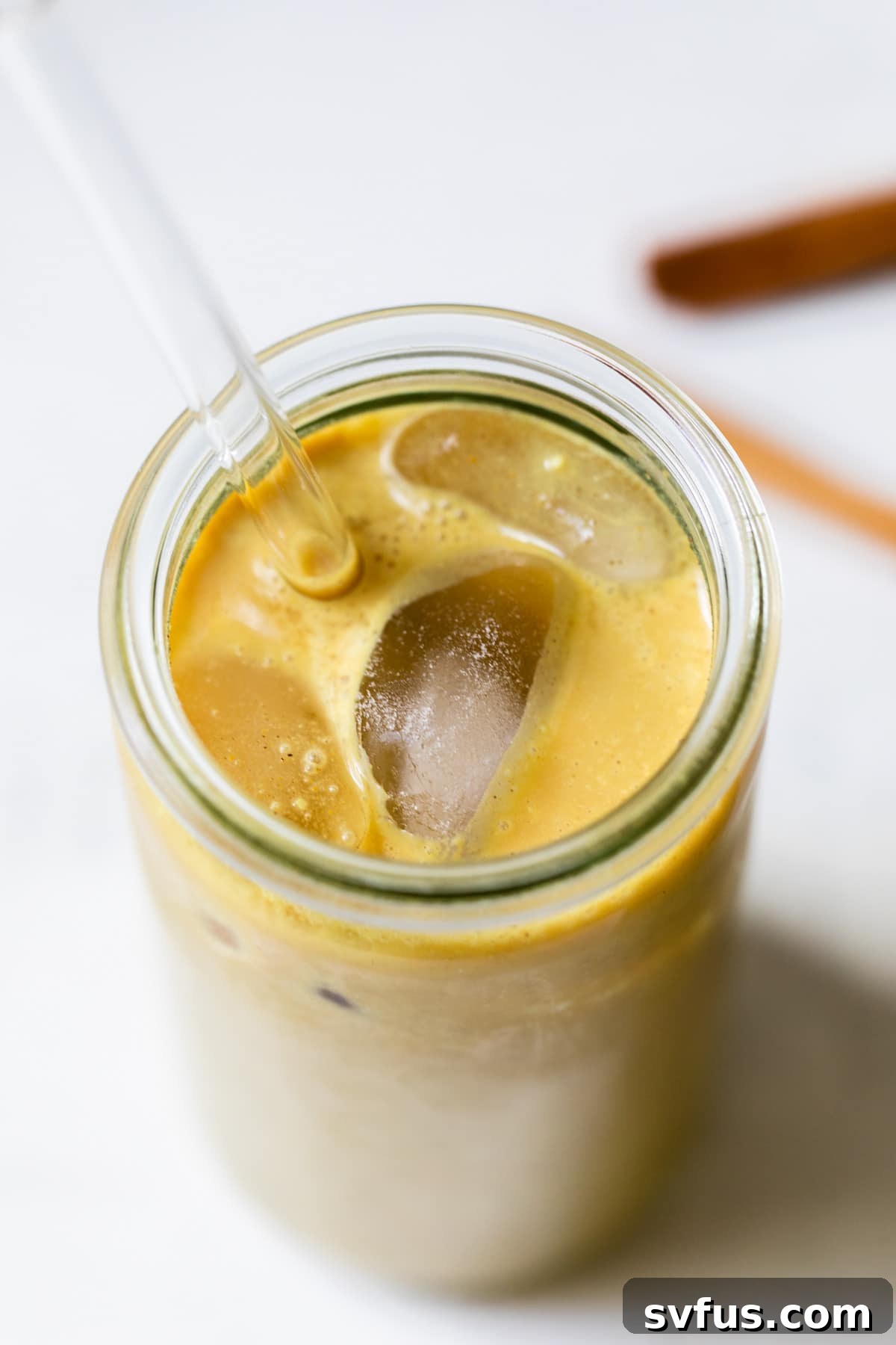 Close up of an iced turmeric latte with a straw