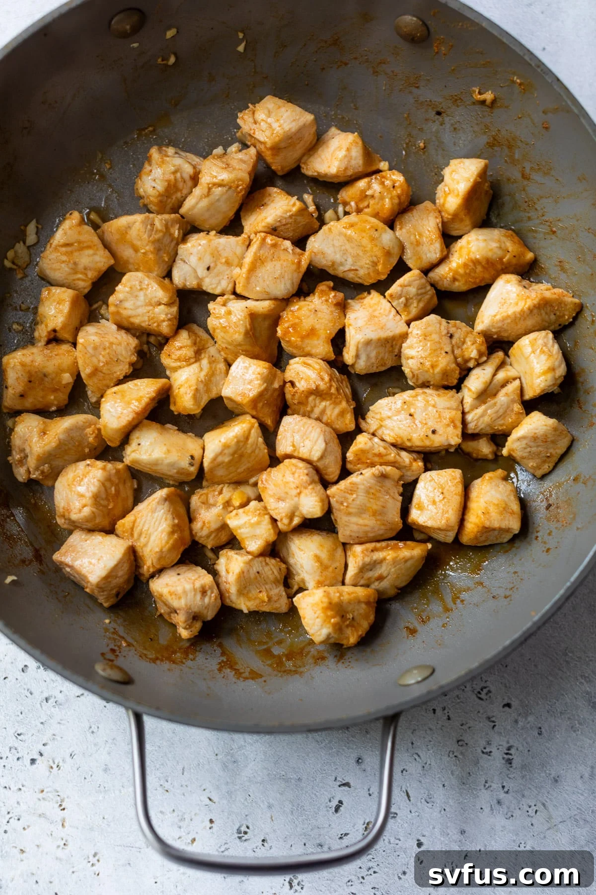 Close-up of chicken bites searing in a hot skillet, developing a golden-brown crust.