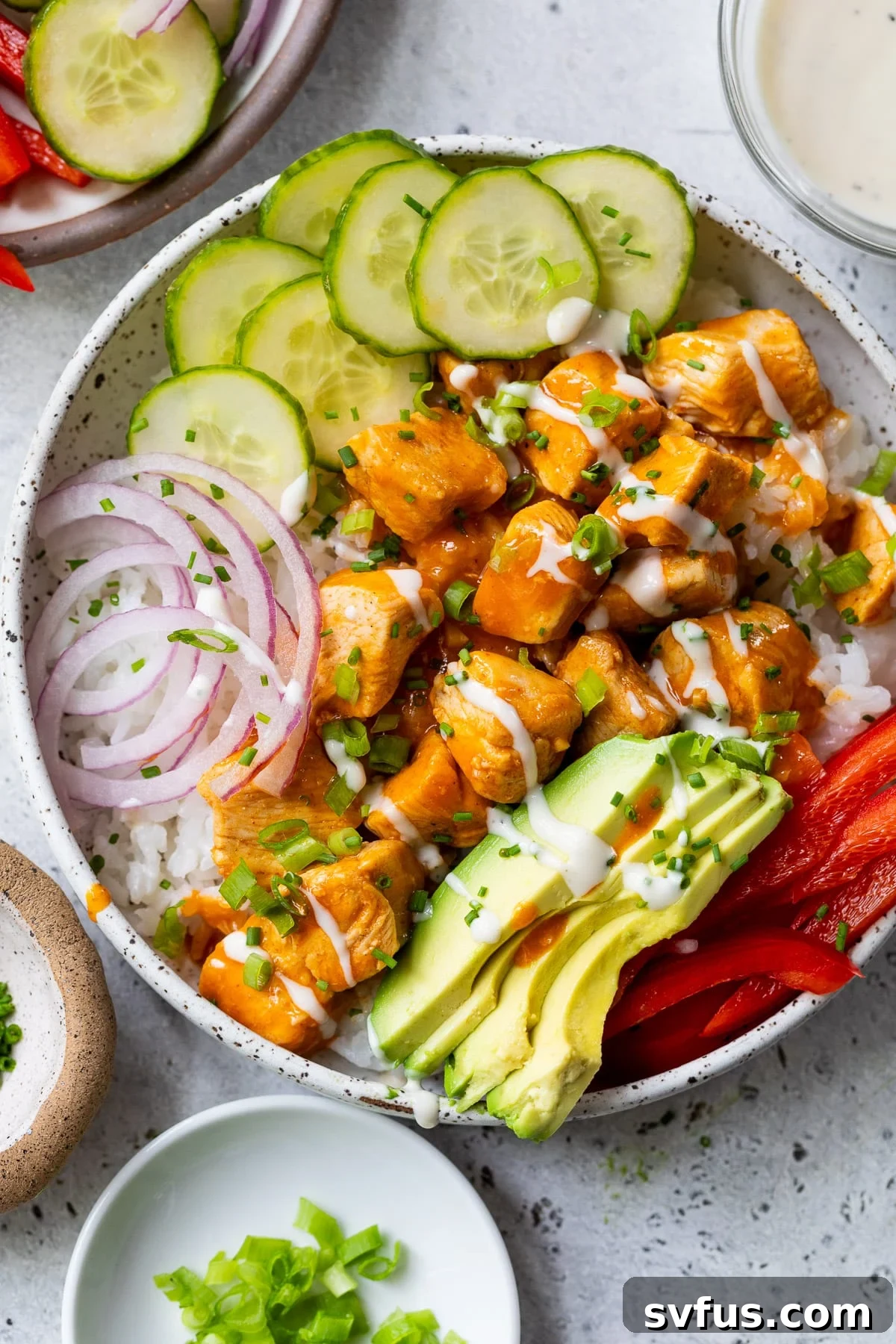 Overhead view of a beautifully assembled Buffalo Chicken Bowl, featuring spicy chicken, fresh cucumber, red onion, and creamy avocado, ready to be enjoyed.