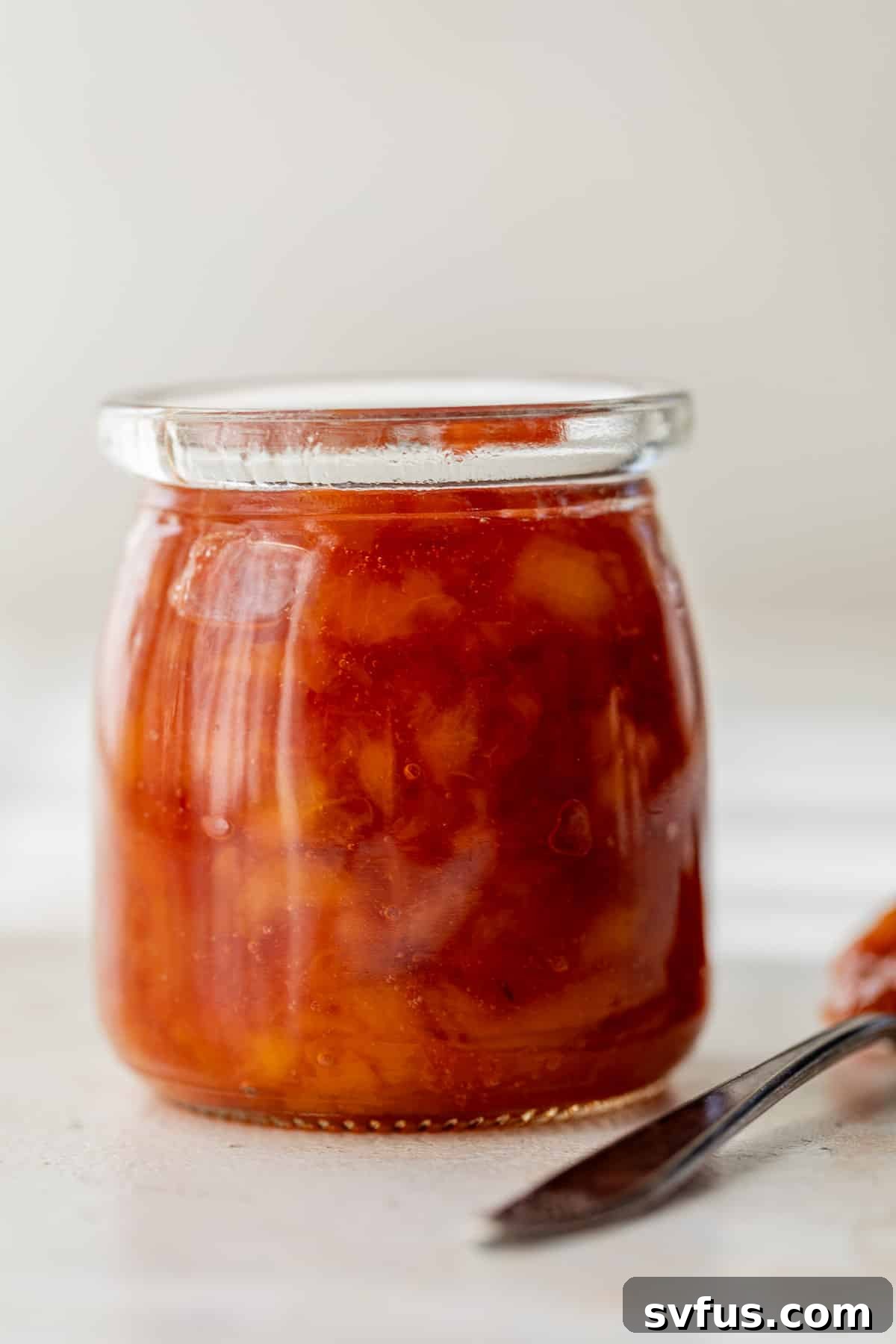 A second close-up image of a glass jar filled with luscious peach preserves, ready to be stored or served.