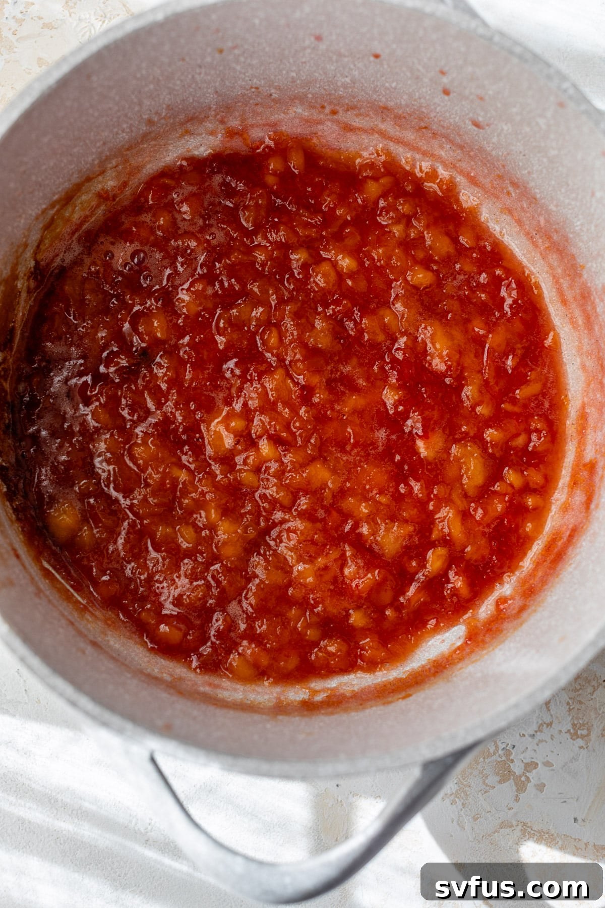 Cooked Peach Preserves simmering in a large pot, showing the thickening process.