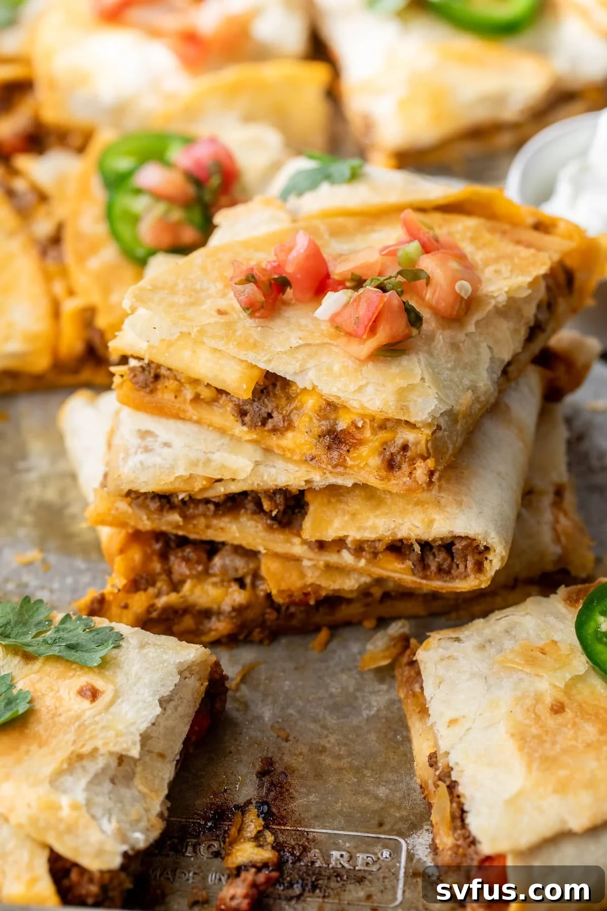 Close up on a stack of golden-brown sheet pan quesadillas, garnished with fresh salsa and cilantro, ready to be served for a fun family dinner.