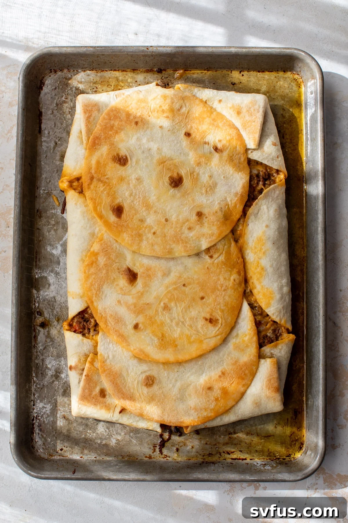 A perfectly baked, golden-brown sheet pan quesadilla resting on a baking sheet, showcasing its crispy texture after emerging from the oven.