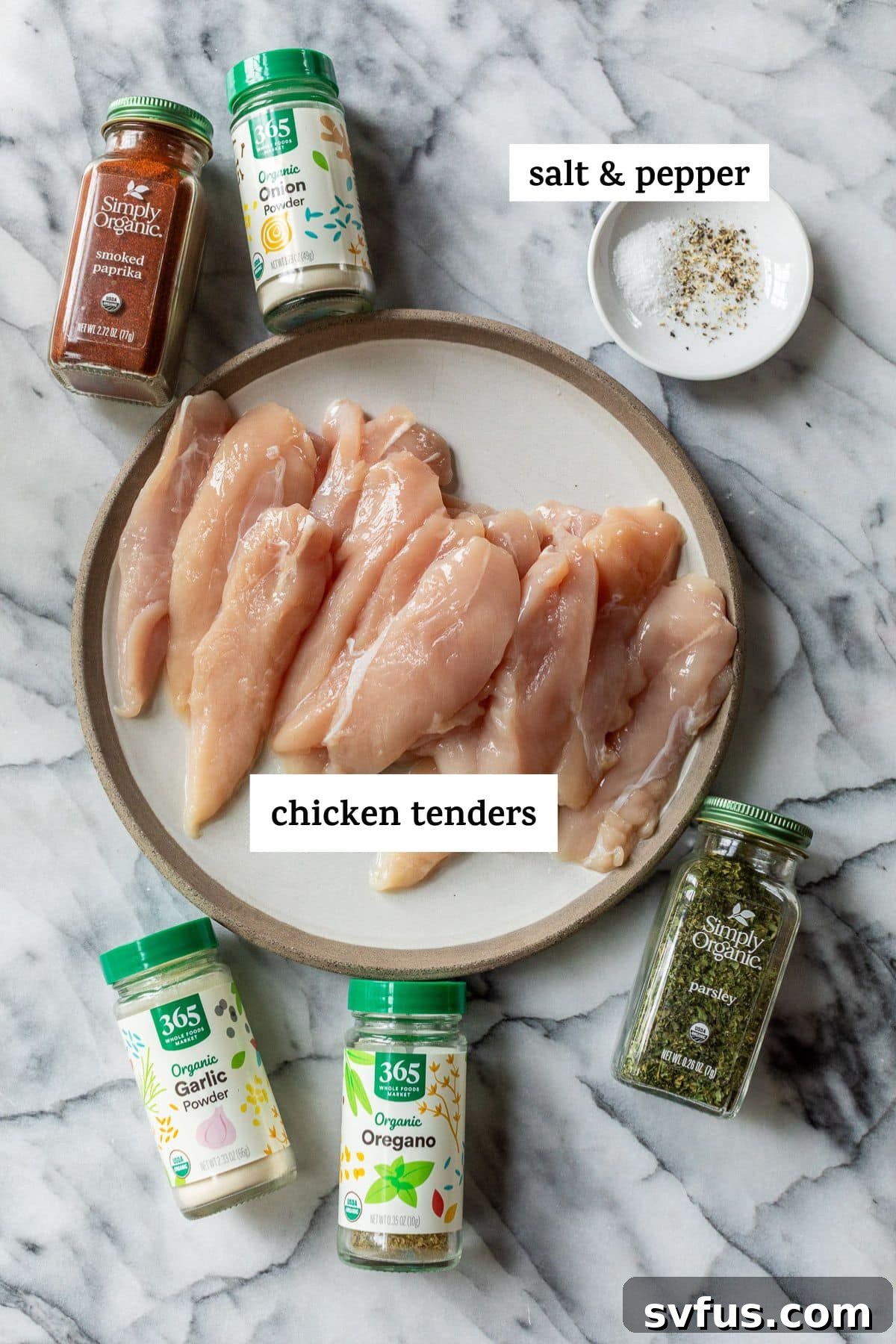 Individual bowls holding garlic powder, smoked paprika, oregano, parsley, salt, and black pepper, along with a separate bowl of raw chicken tenders – all neatly arranged for a cooking demonstration.