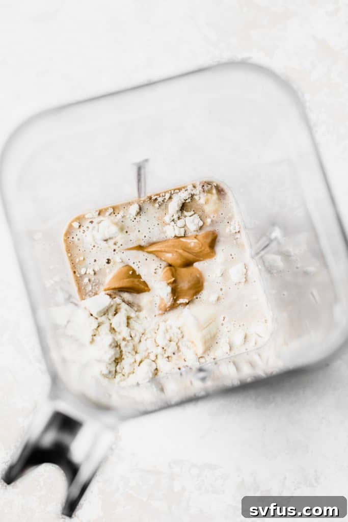 A vibrant cold brew protein smoothie in a clear glass, showing its creamy texture, with coffee beans scattered around.