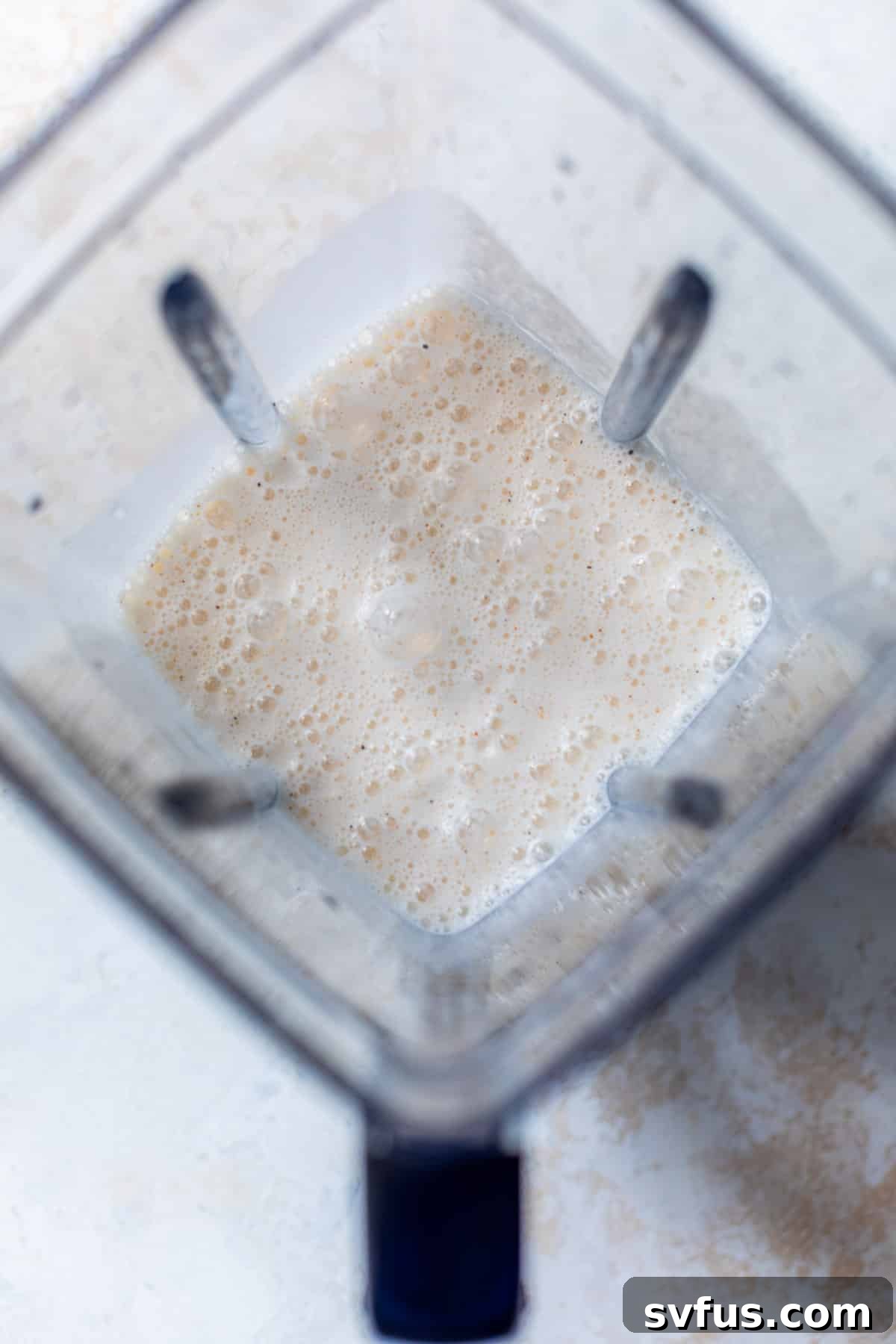 a bubbly white cottage cheese sauce blending in a blender, becoming perfectly smooth.