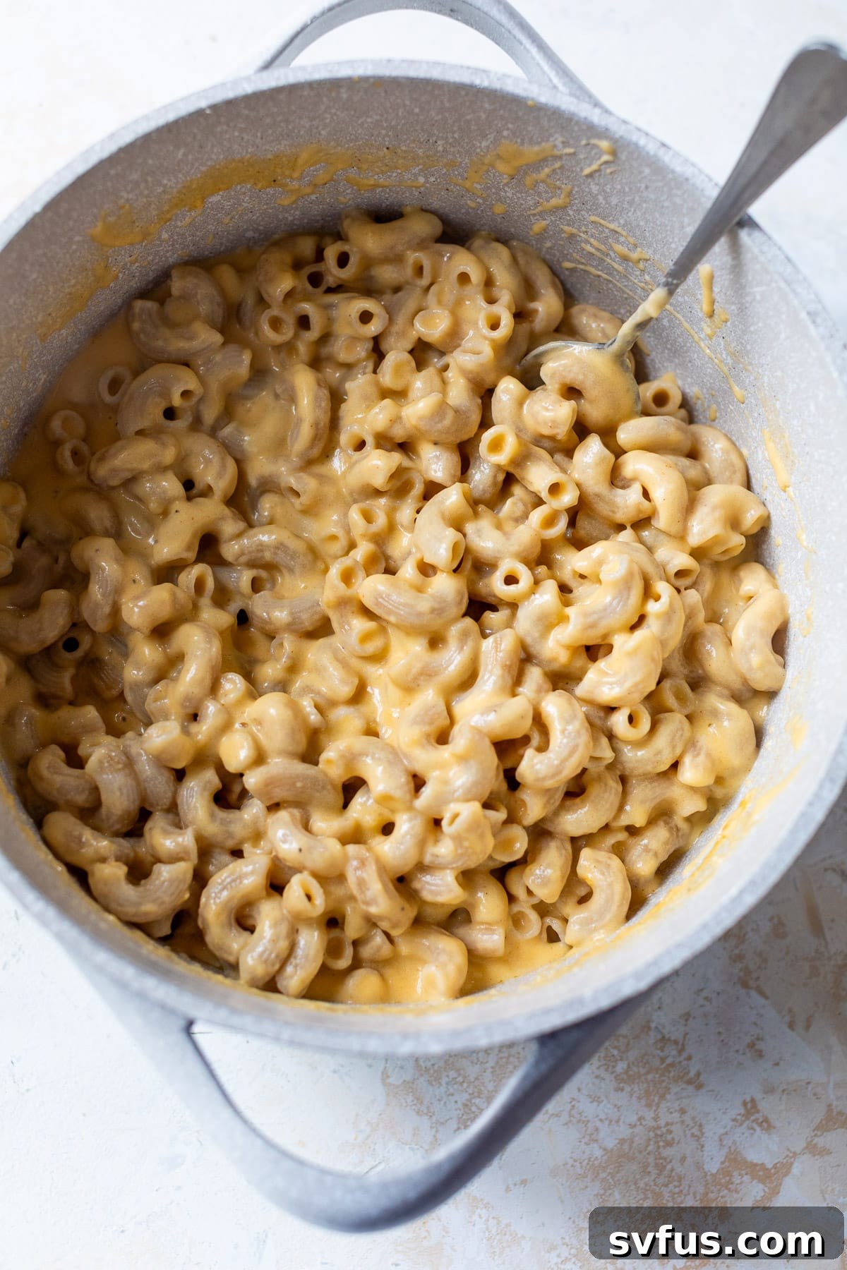 overhead view of a large pot filled with freshly combined cottage cheese mac and cheese, ready to serve.