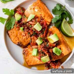 Two salmon fillets on a plate topped with salsa and diced avocado, showcased as the finished dish.