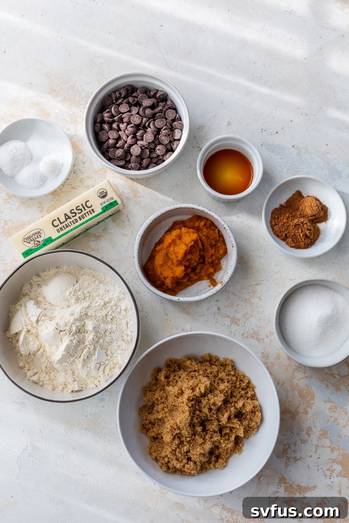 The ingredients for Pumpkin Chocolate Chip Cookies laid out in individual white bowls.
