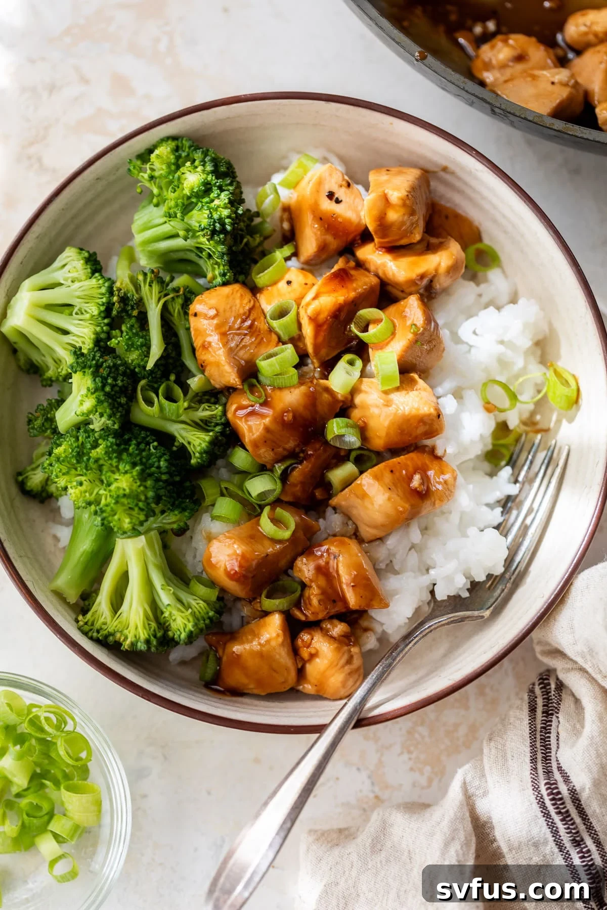 Teriyaki chicken and broccoli served over white rice in a bowl, ready to eat.