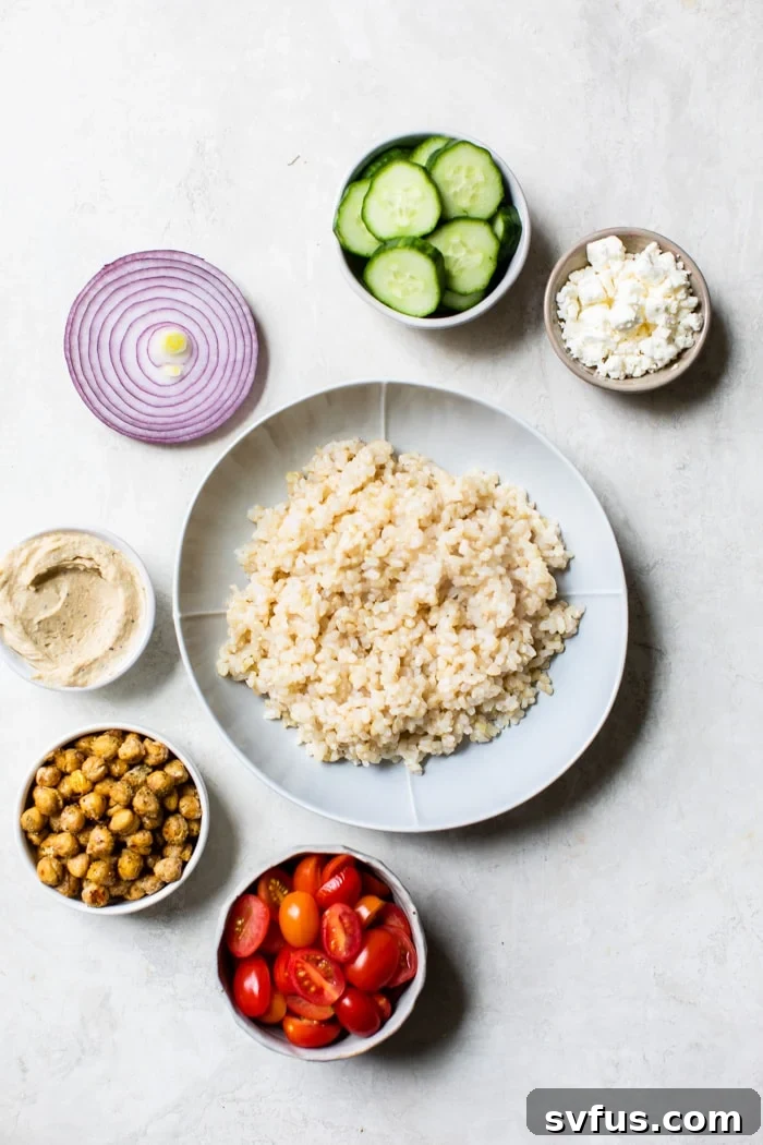 Two Mediterranean Hummus Bowls, beautifully assembled with rice, various fresh vegetables, feta, and a dollop of hummus, ready to be enjoyed.