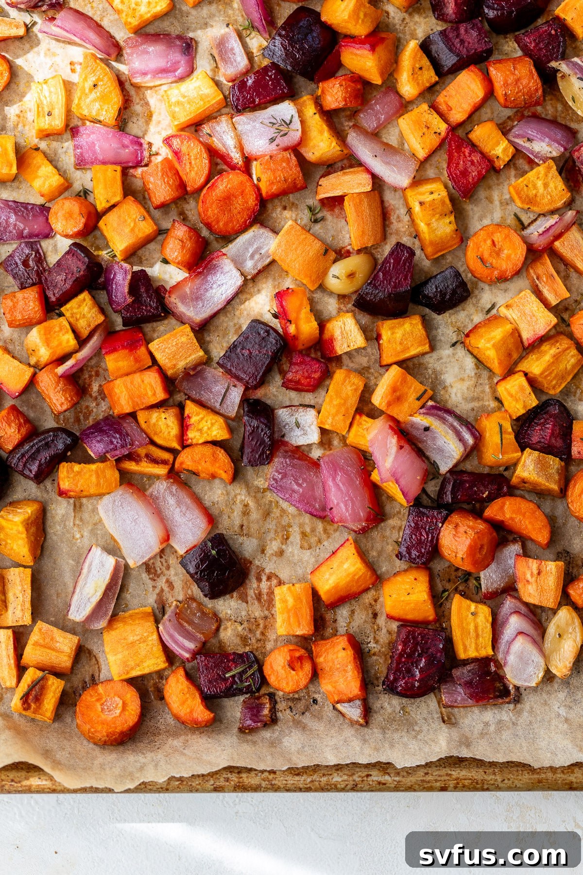 Overhead view of a perfectly roasted medley of root vegetables on a sheet pan, showing tender vegetables with caramelized edges.