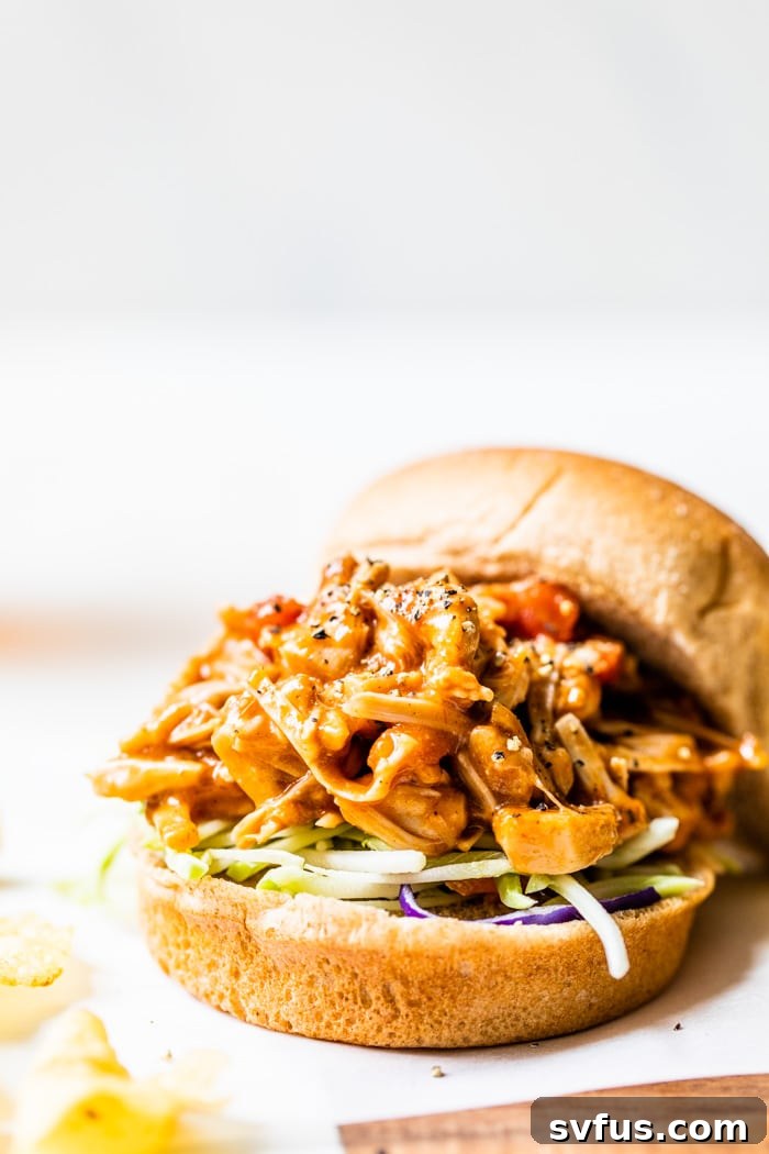 A close-up shot of a gourmet hamburger bun generously filled with savory barbecue pulled jackfruit, showcasing the rich texture and delicious appeal of this vegan dish.