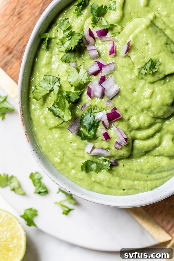 Guacamole salsa drizzled over a plate of chips and tacos, showcasing its versatility.