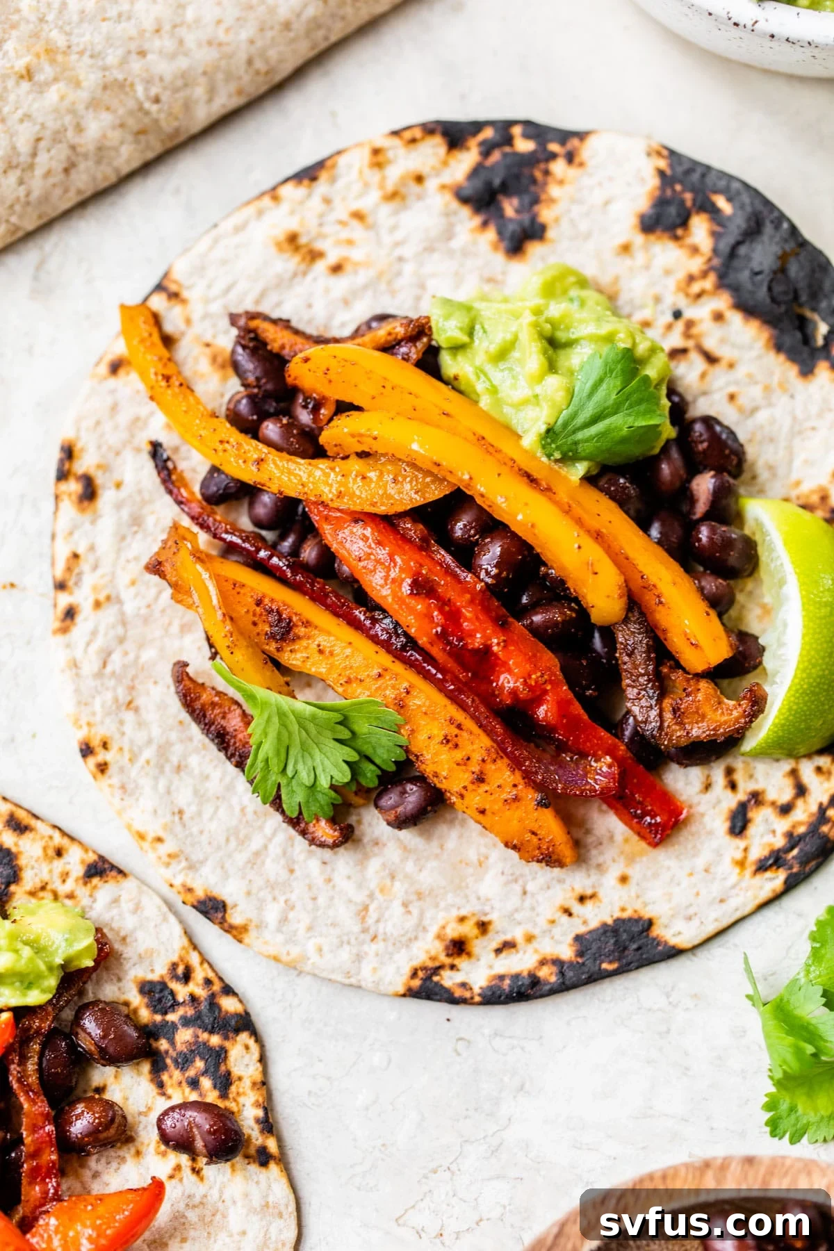 Flavorful vegetarian fajitas served with black beans and fresh guacamole, ready for a satisfying meal.