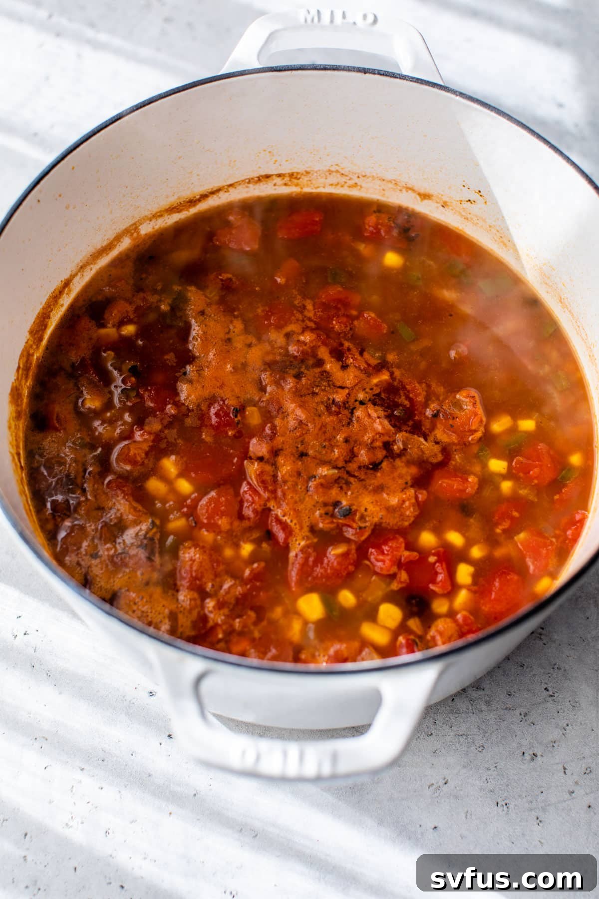 All vegan tortilla soup ingredients simmering gently in a Dutch oven, with steam rising.