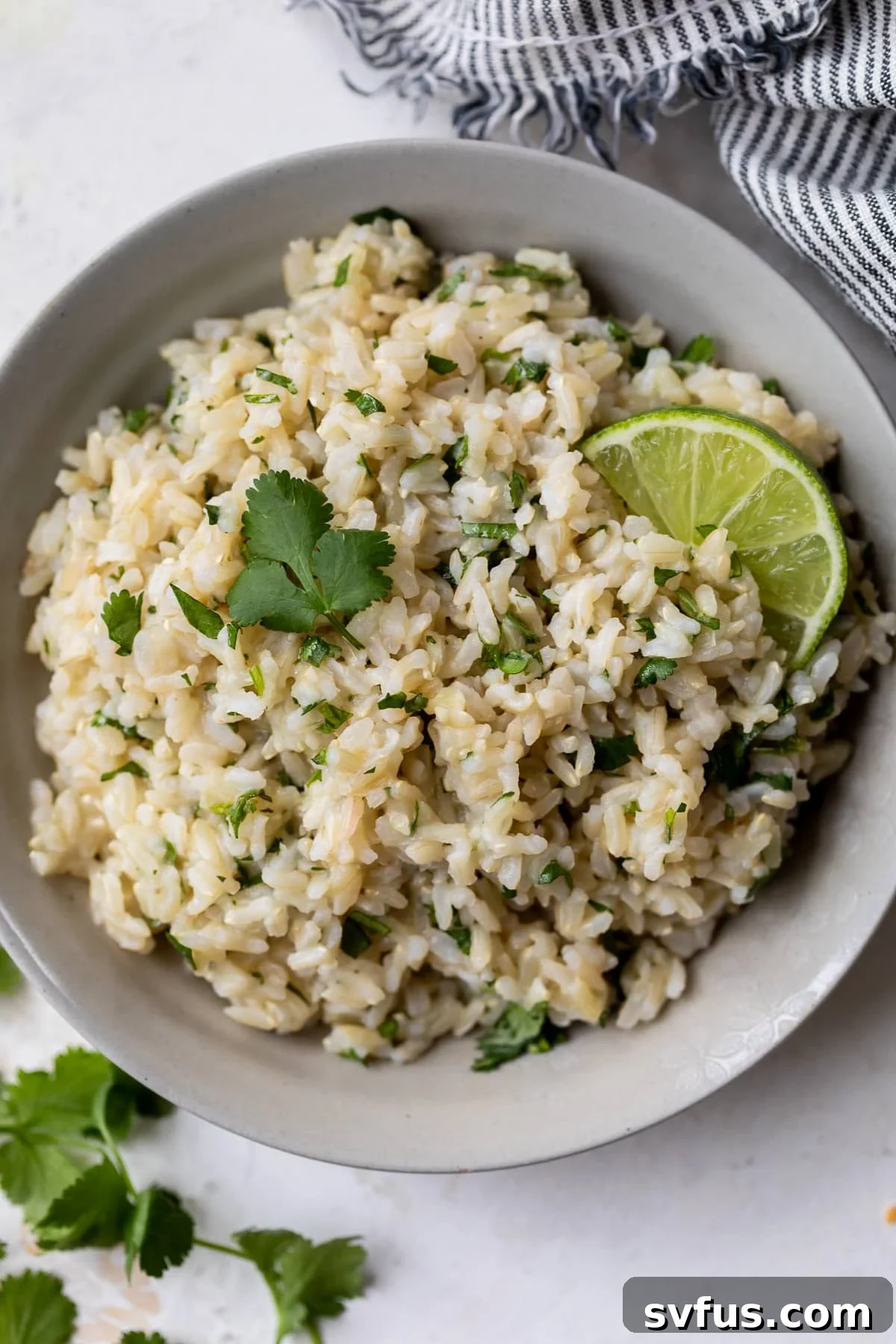 A bowl of Cilantro Lime Brown Rice with a lime wedge, showcasing its delicious appeal as a versatile and healthy meal option.