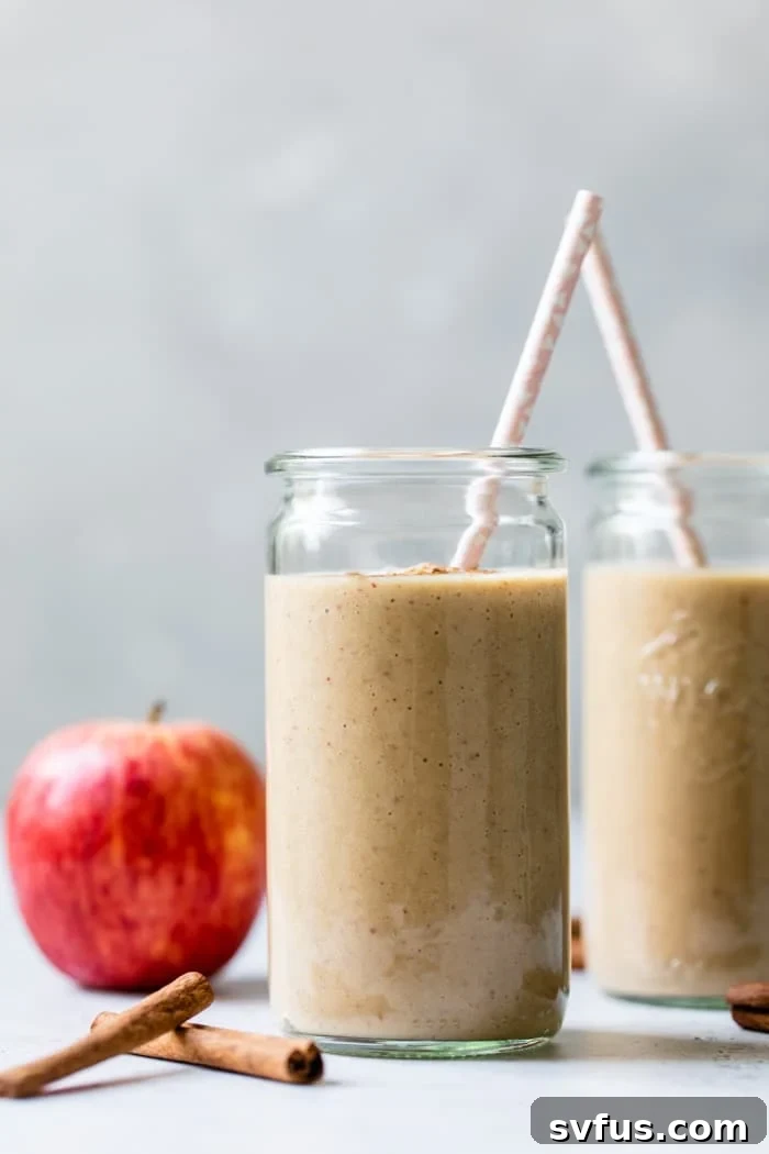 A vibrant, perfectly blended apple smoothie, garnished with a fresh apple slice and a sprinkle of cinnamon, ready to be enjoyed.