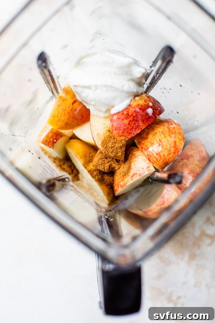A blender filled with the creamy apple smoothie mixture, halfway through blending, showcasing the transformation of ingredients into a smooth beverage.